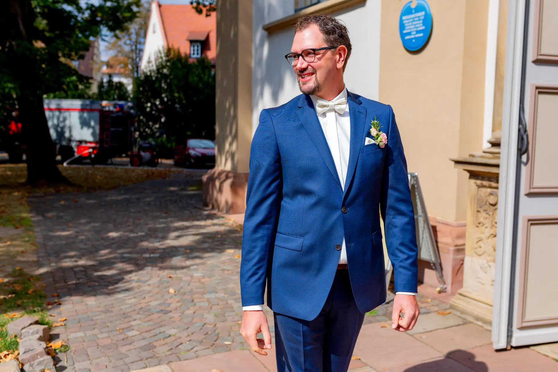 20180915 13 29 57 MK3 4876 Brautpaar Hochzeit Anzug Blume Hochzeitsfotograf Reilingen Speyer Ida Philipp.BWUL A Y Brautpaar im eleganten Marineblau vor dem Kirchenportal bei sonnigem Wetter