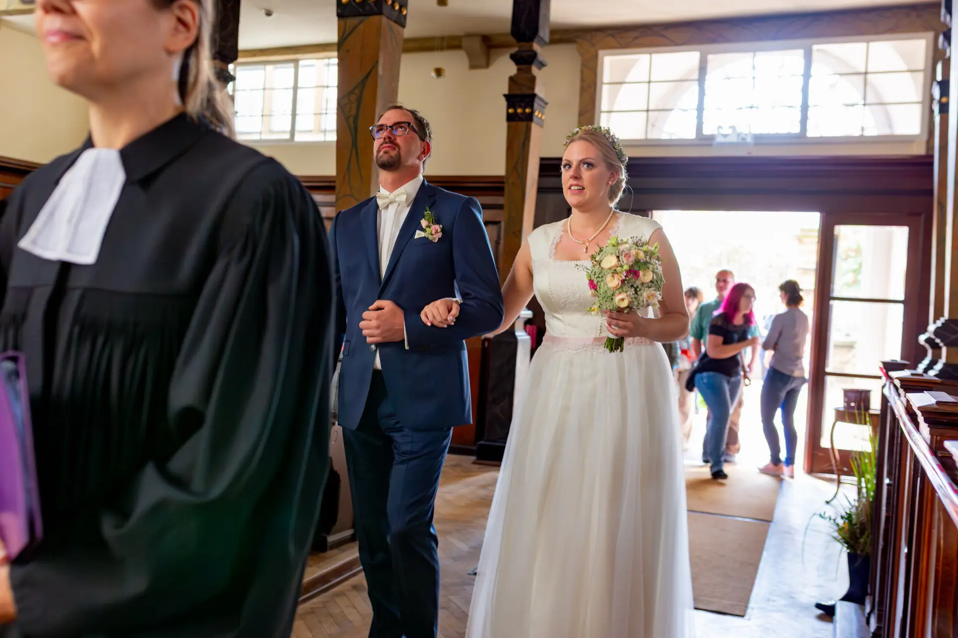 20180915 13 34 14 MK3 5058 Hochzeit Braut Kirche Familie Hochzeitsfotograf Reilingen Speyer Ida Philipp.NvkD6GkO Brautpaar geht zur Kirche, umgeben von Holzbalken und Blumen