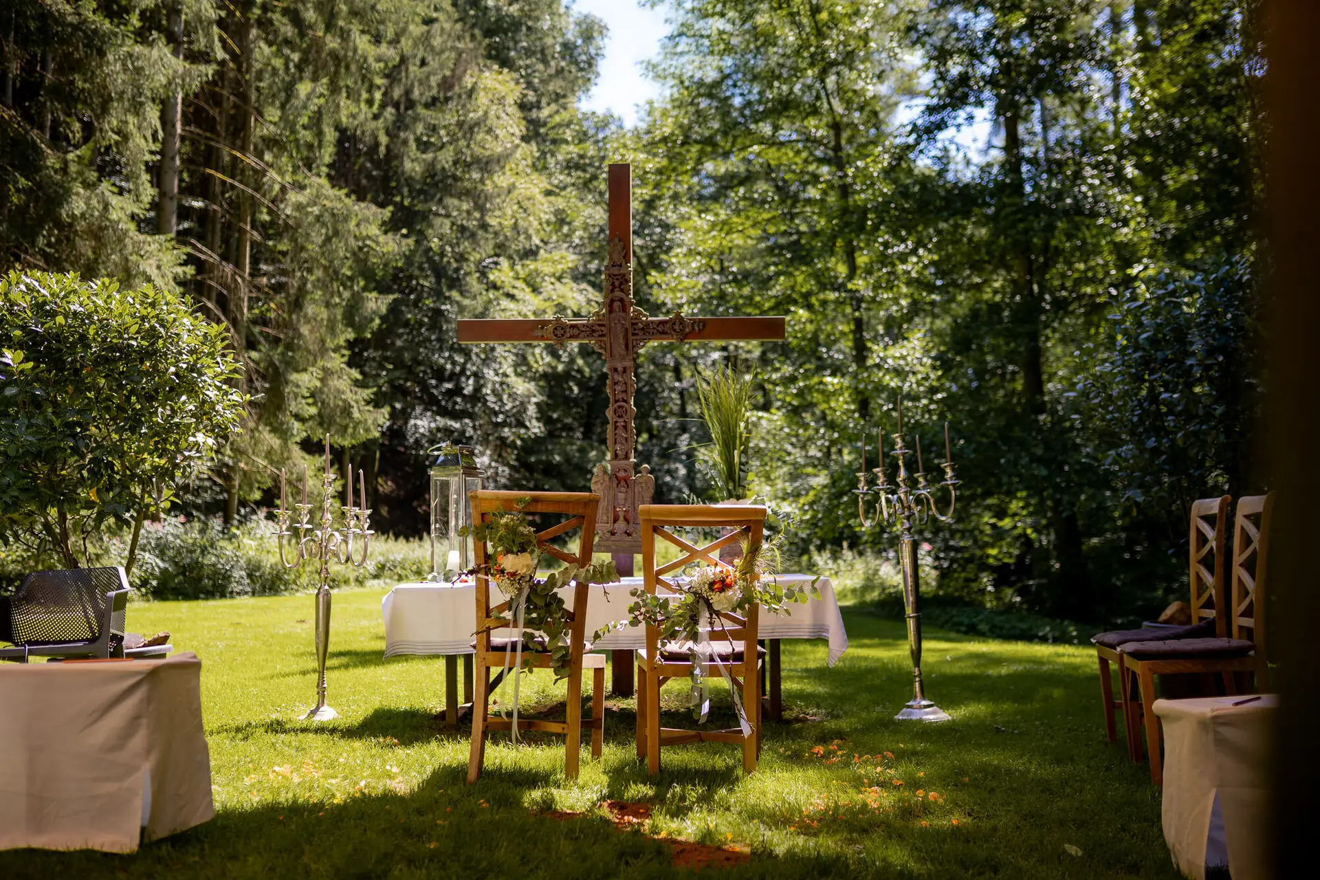 20230811 13 33 41 Hochzeit Elztal Hochzeitsfotograf Heiraten Heidelberg Landgasthof Heidersbacher Muehle 4K8A0437.B7KbsRX4 Romantische Trauungskulisse im Wald – Holzkreuz, floraler Schmuck, Stühle und Kerzenleuchter unter freiem Himmel