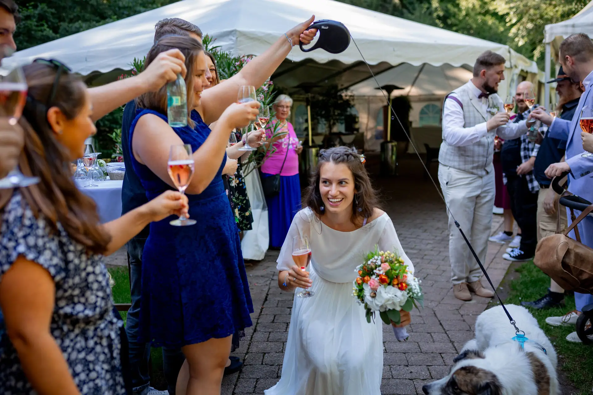 20230811 15 36 44 Hochzeit Elztal Hochzeitsfotograf Heiraten Heidelberg Landgasthof Heidersbacher Muehle 4K8A4809.DUDe6cbh Braut lacht herzlich mit Gästen beim Champagner-Empfang im Freien der Heidersbacher Mühle