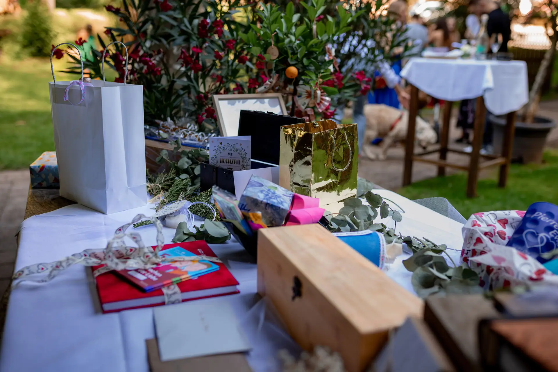 20230811 16 21 39 Hochzeit Elztal Hochzeitsfotograf Heiraten Heidelberg Landgasthof Heidersbacher Muehle 4K8A5230 Verbessert RR.COod4FLX Geschenke und goldenes Fotoalbum auf dem Empfangstisch – liebevoll arrangiert