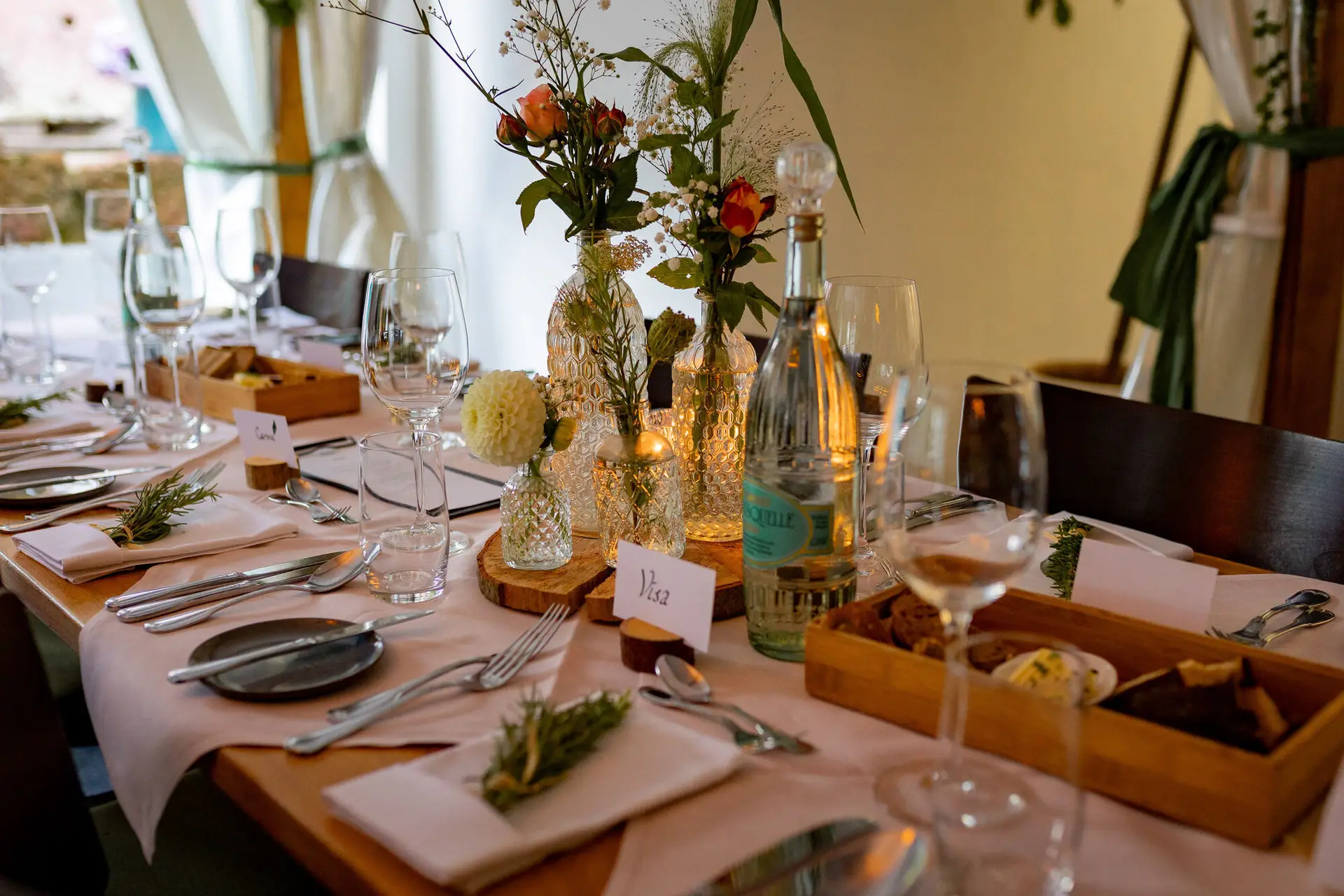 20230811 18 39 45 Hochzeit Elztal Hochzeitsfotograf Heiraten Heidelberg Landgasthof Heidersbacher Muehle 4K8A7253.Bk Pgssq Langer Festtisch mit hellrosa Tischdecken und Holzscheiben, Gäste versammeln sich zum Abendessen