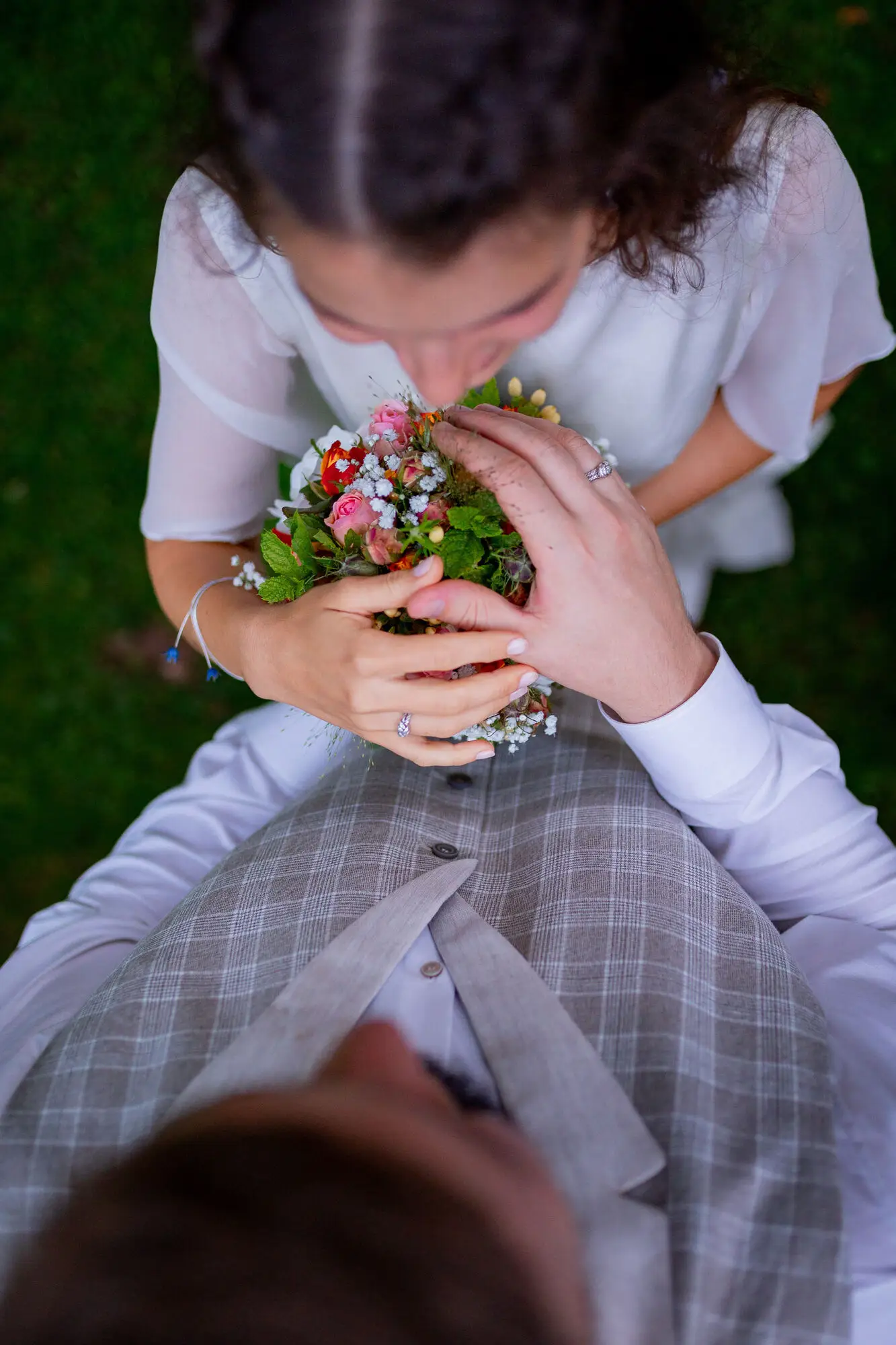 20230811 20 53 29 Hochzeit Elztal Hochzeitsfotograf Heiraten Heidelberg Landgasthof Heidersbacher Muehle 4K8A8518.DLcZVRS6 Brautpaar sitzt auf der Wiese mit Blumengirland beim goldenen Abendlicht des Elztals