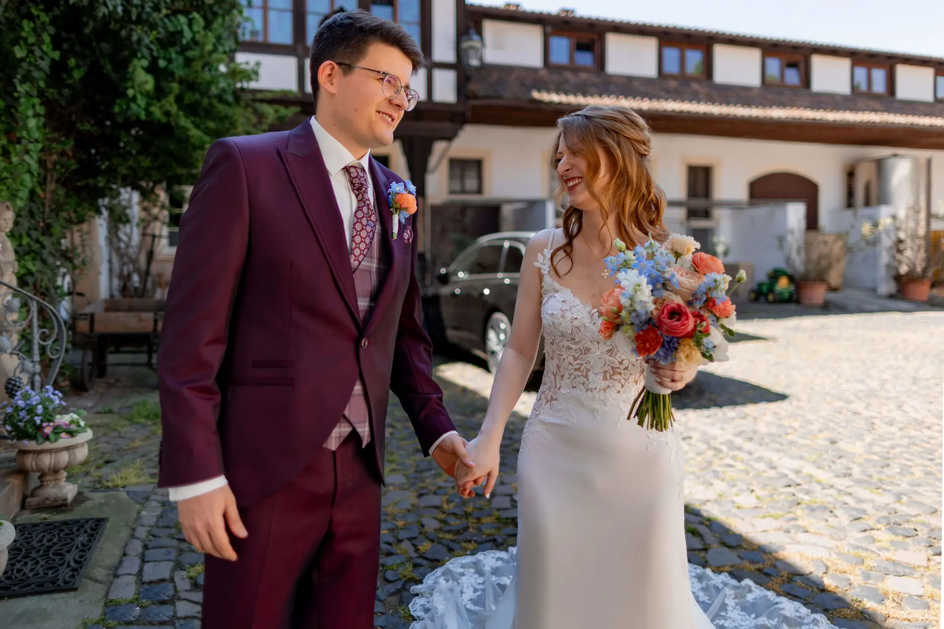 Strahlendes Brautpaar lacht und hält Händchen beim First Look im Innenhof