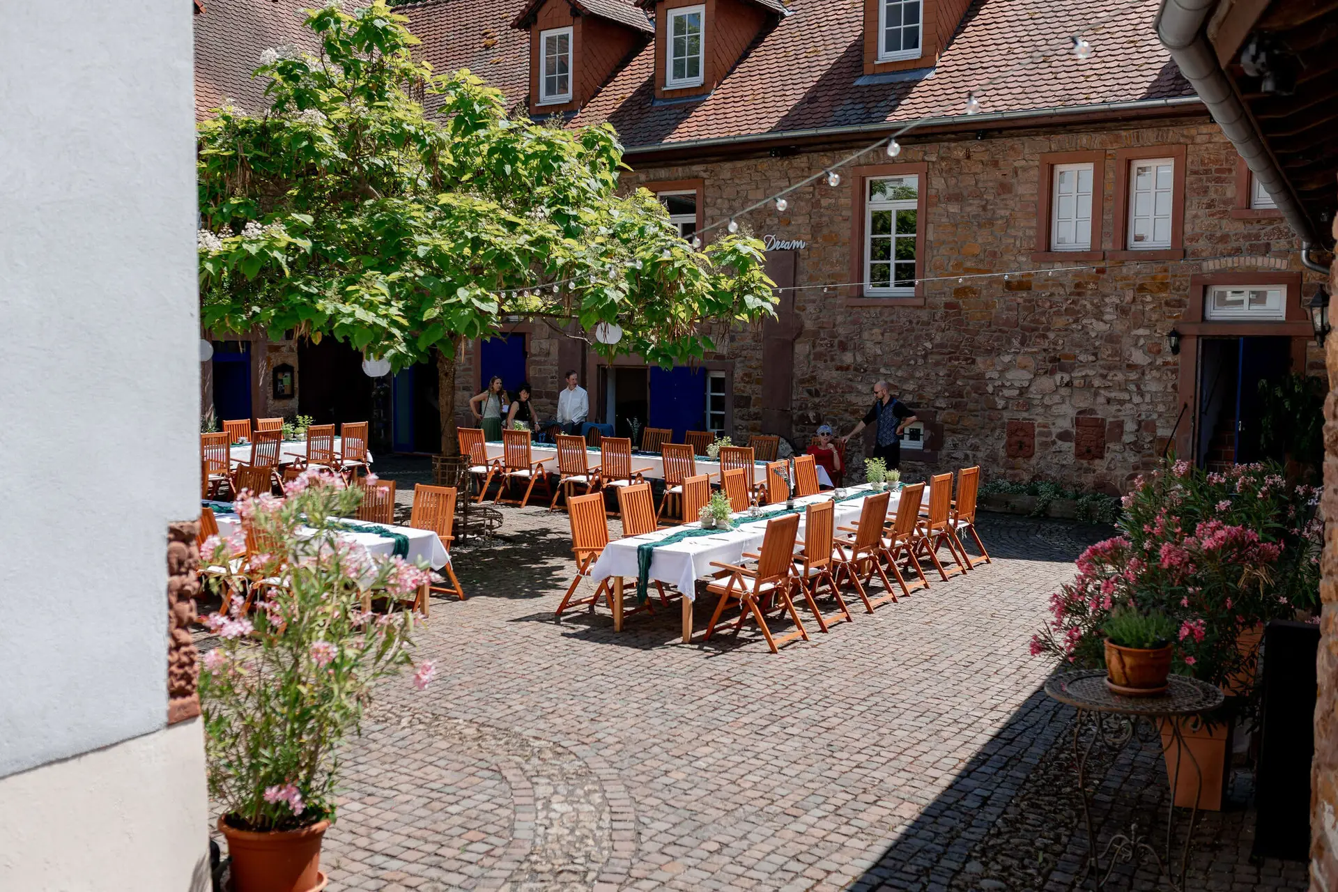 Innenhof mit aufgebauten Hochzeitstischen und Holzstühlen