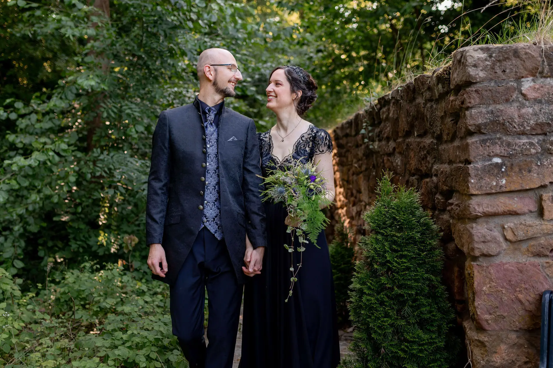 Hochzeitsringe in der Hand mit Garten im Hintergrund