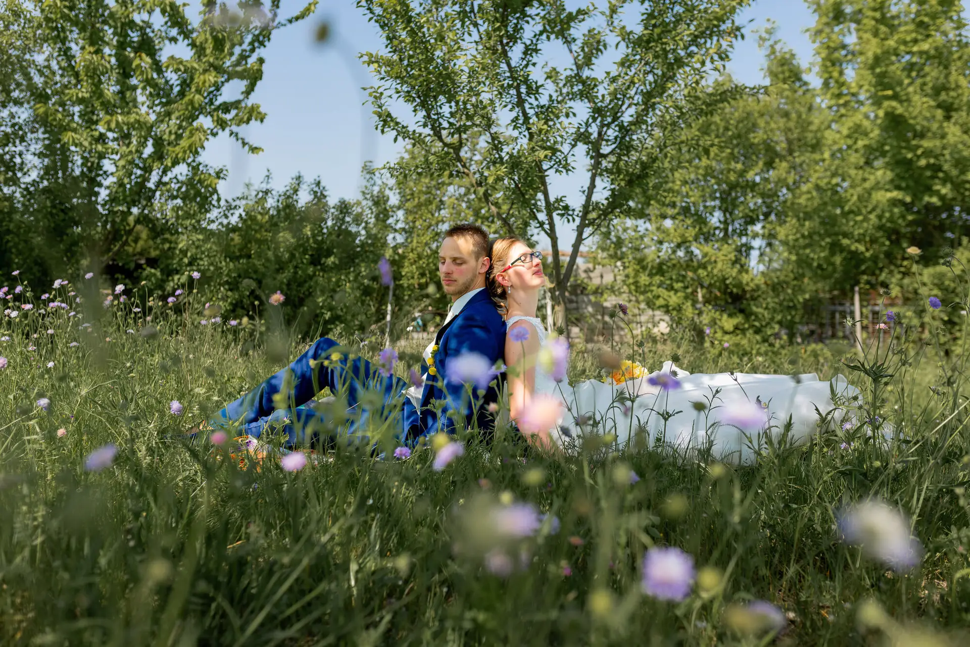 Anne Christian Hochzeitsfotograf Birkenheide Grosskarlbach Bissersheim 00021.DL8uecyb Hochzeitspaar sitzt auf Wiese mit Lavendelblüten im Hintergrund und blickt gemeinsam in die Ferne
