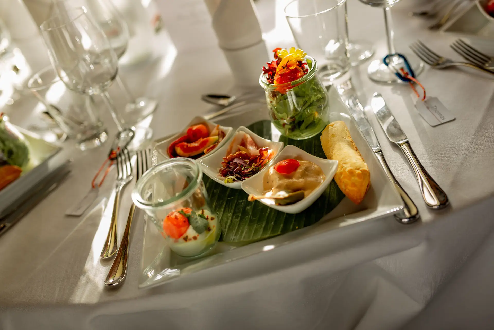 Anne Christian Hochzeitsfotograf Birkenheide Grosskarlbach Bissersheim 00032.D0cXCI9Z Tablett mit kleinen Vorspeisen – Salat, Garnelen, Dip und Brot – auf weißem Hochzeitstisch