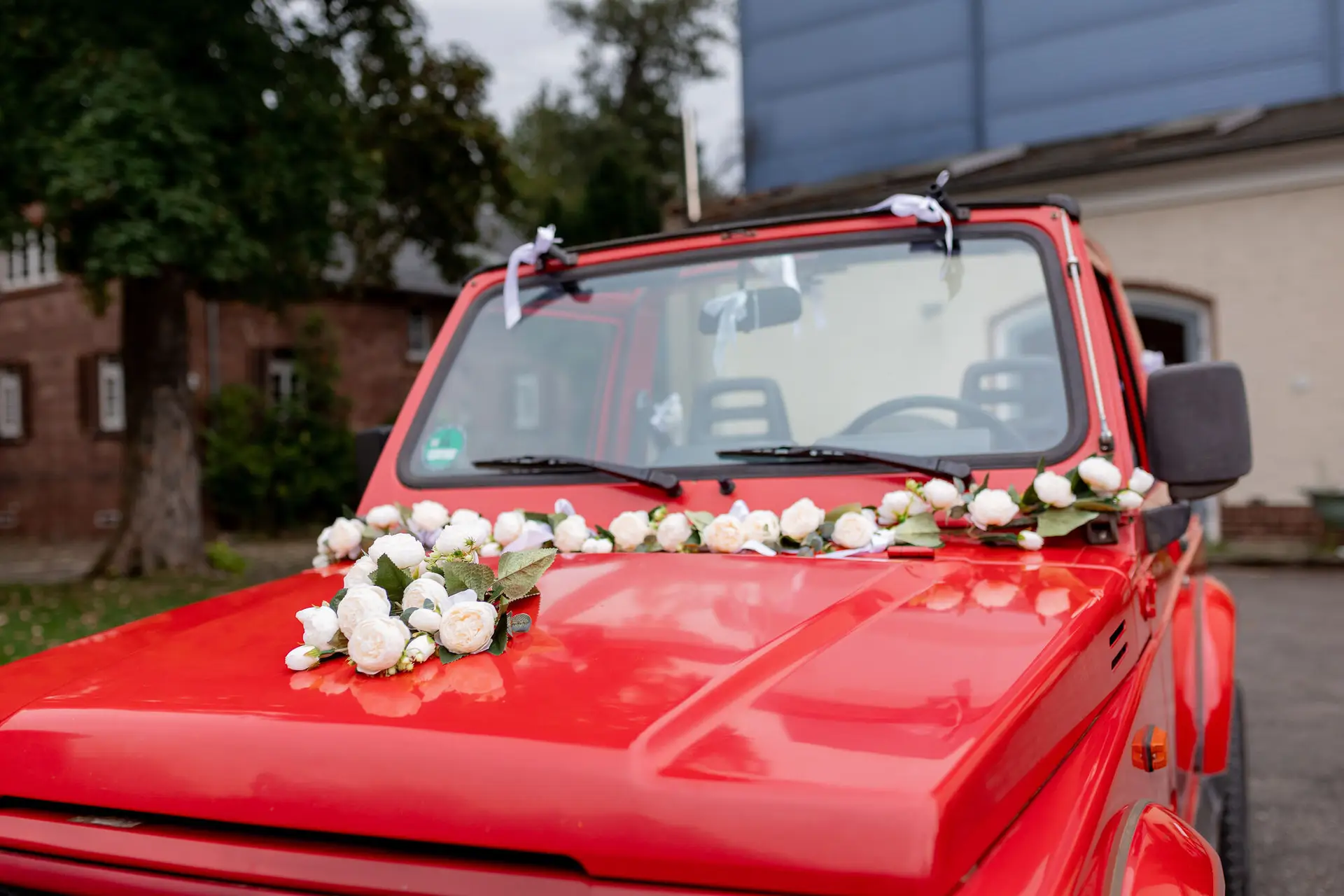 Daniela Matthias Rotes Auto Motorhaube Rosen.B36mJpPY Motorhaube des roten Hochzeitsfahrzeugs mit weißen Rosen dekoriert