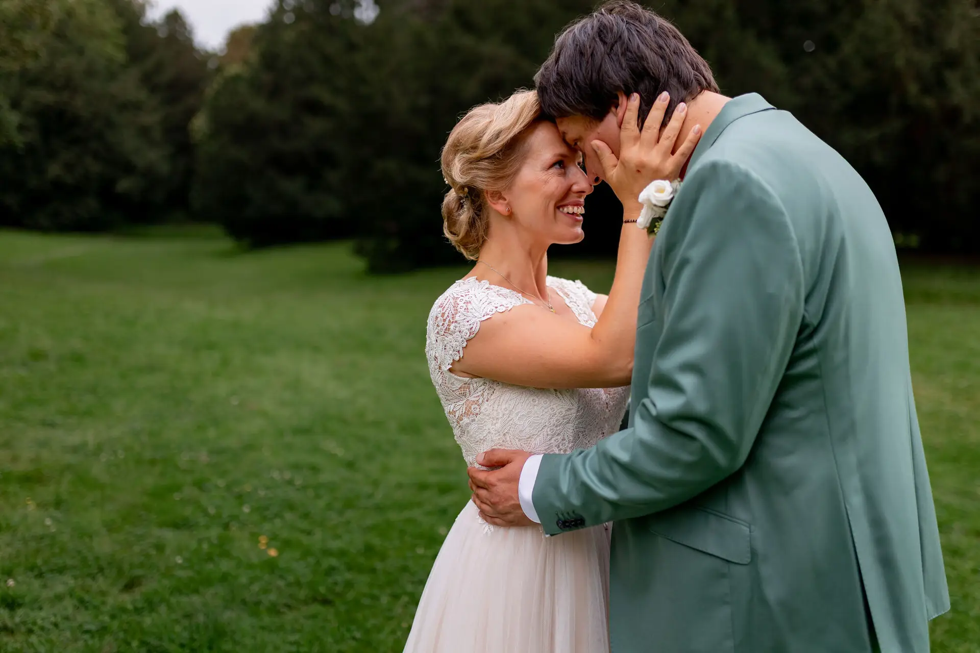 Daniela Matthias Schlossgarten Braut Lacht Gluecklich.CcgArctj Strahlende Braut im weißen blumigen Kleid hält den Arm des Bräutigams, Braut lacht glücklich während sie das Gesicht des Bräutigams berührt im Schlossgarten Karlsruhe
