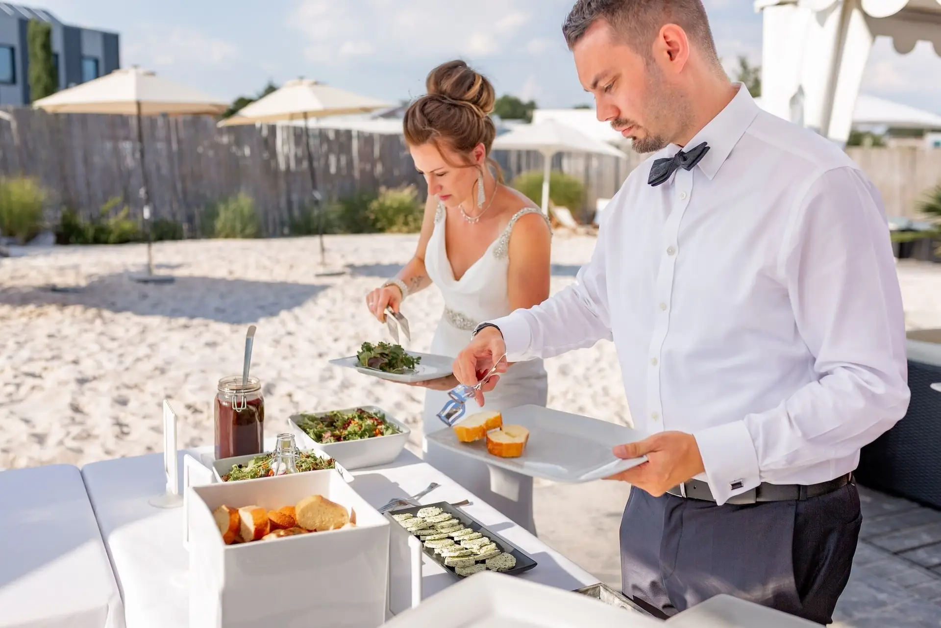Bräutigam serviert der Braut am Buffet auf dem Strand, entspannter Moment beim Empfang