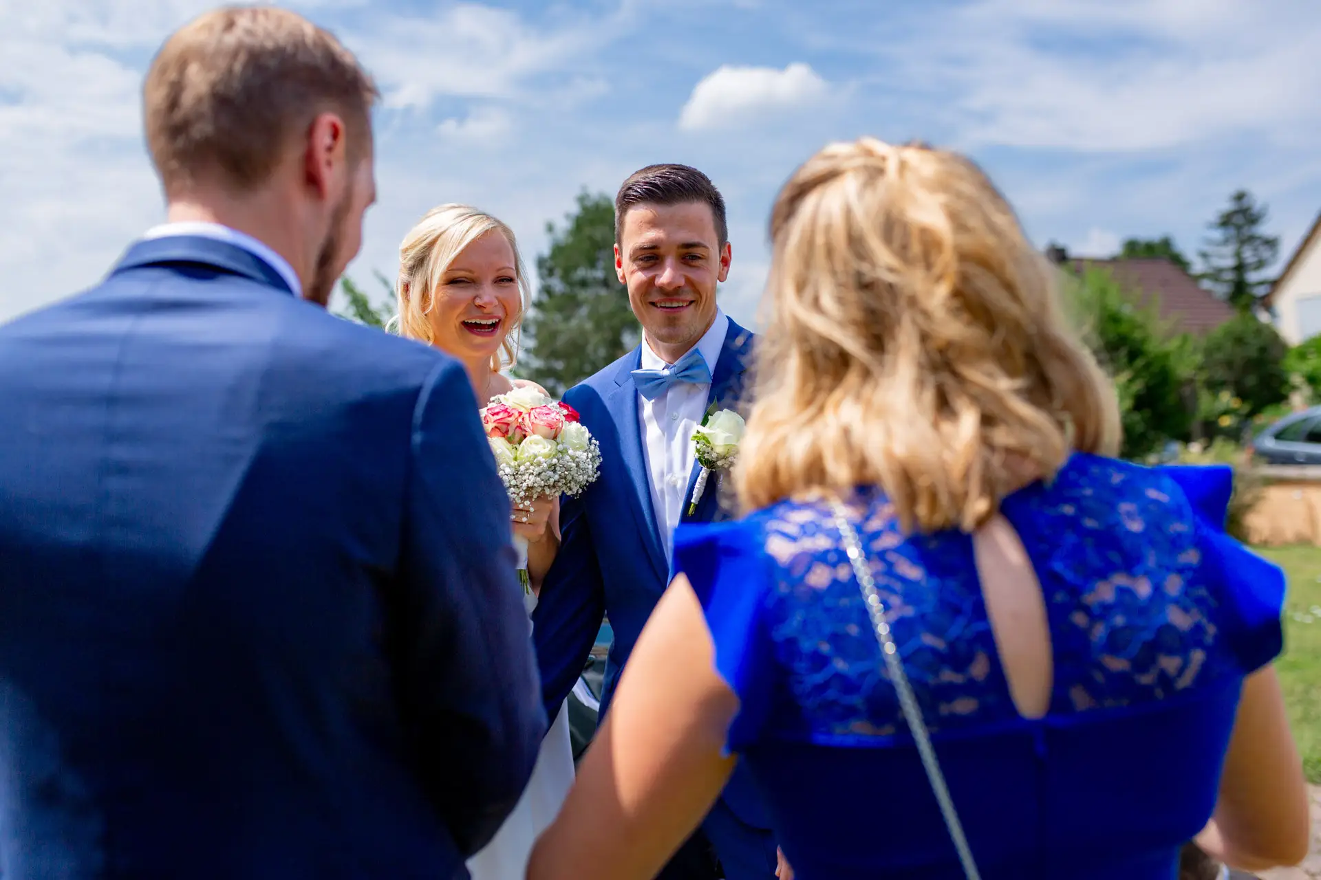 Liane und Kevin lachen mit Gästen nach der Trauung am Schlosspavillon