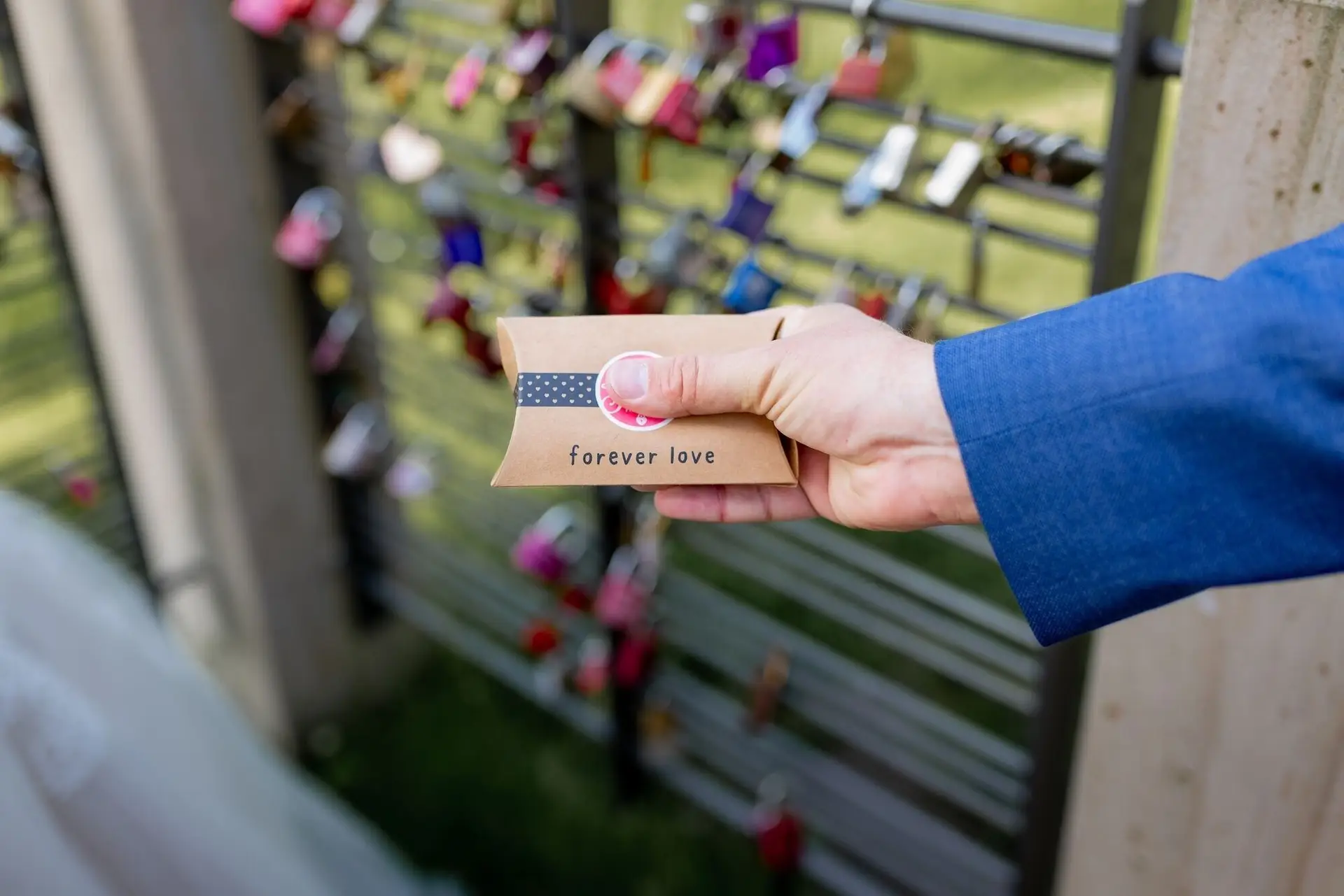 Tina Bjoern Kurpark Forever Love Karte Liebesschloss.IB0vaqBe Hand hält kleine 'forever love'-Karte vor dem Liebesschloss-Geländer im Kurpark Bad Dürkheim