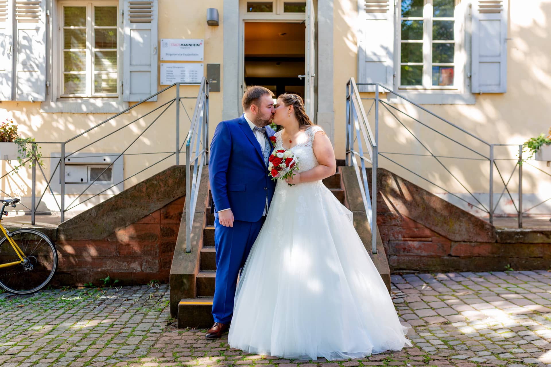 20210903 11 26 40 Wenz Brautpaar Treppe Standesamt MK3 4301.CvHgVis4 Brautpaar steht auf der Steintreppe vor dem Standesamt mit Brautstrauß und Fahrrad im Hintergrund