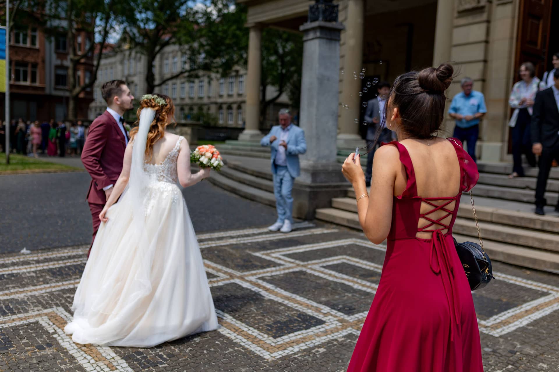 20230610 13 55 12 4K8A9769 Hochzeitsfotograf Mannheim Christuskirche Neuleiningen Burgschenke.DXQRb6wV Braut mit Blumenstrauß beim Auszug, Brautjungfer bläst Seifenblasen als Willkommensgruß für das Ehepaar