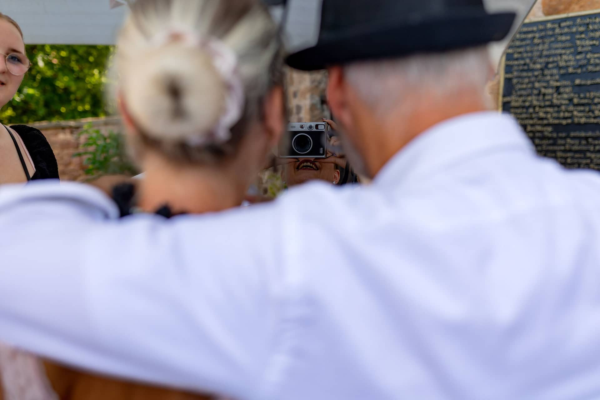 20230610 16 17 27 4K8A2374 Hochzeitsfotograf Mannheim Christuskirche Neuleiningen Burgschenke.Cytz9Weu Älterer Gast mit schwarzem Zylinder fotografiert eine junge Frau beim Hochzeitsfest auf der Burg Neuleiningen