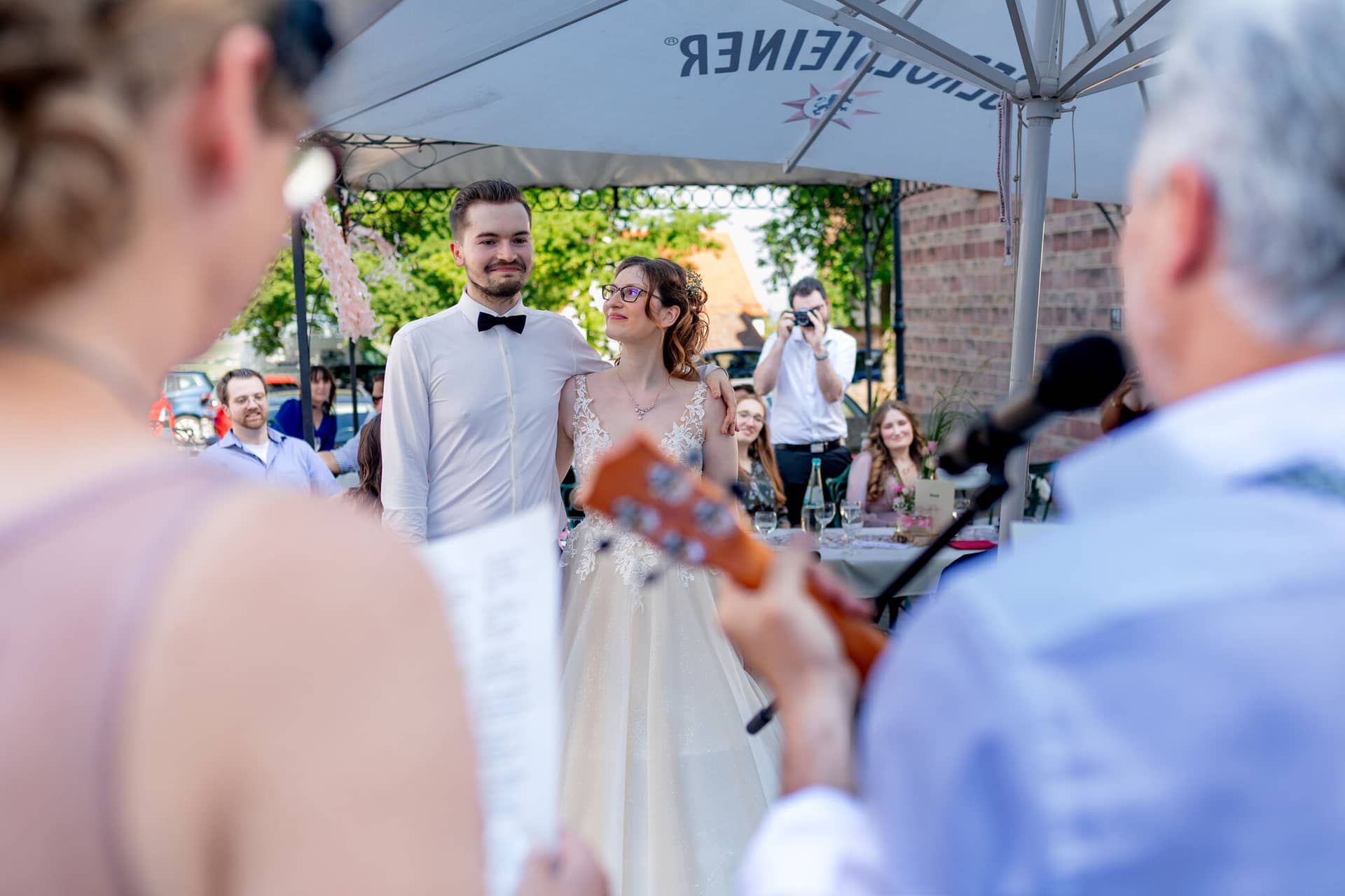 20230610 17 12 03 4K8A2584 Hochzeitsfotograf Mannheim Christuskirche Neuleiningen Burgschenke.DJNiZxRj Brautpaar steht sich beim Brautpaarshooting auf einer Straße gegenüber mit Musikinstrument und Stadtszene im Hintergrund