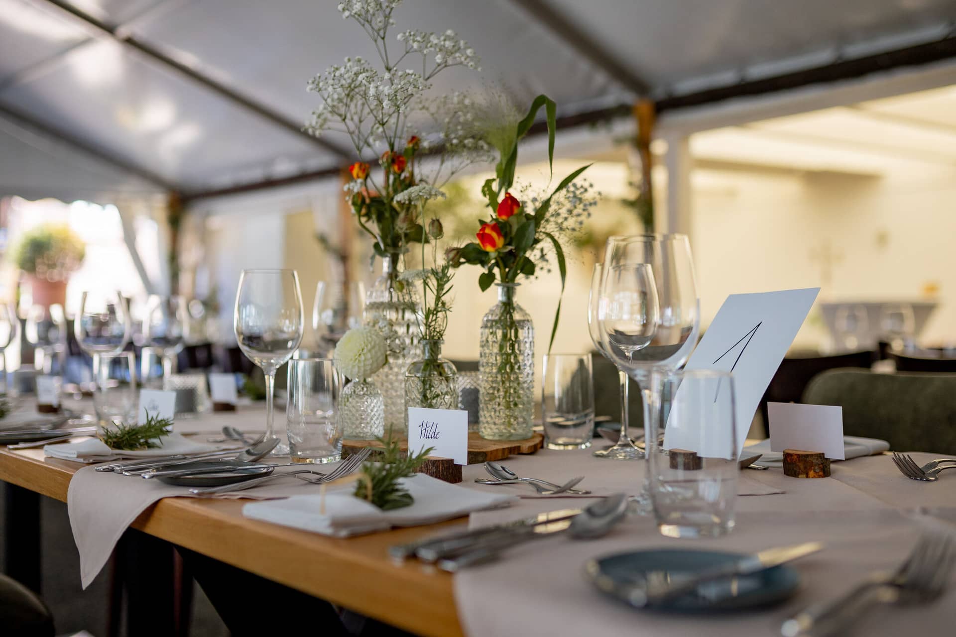 20230811 13 27 33 Hochzeit Elztal Hochzeitsfotograf Heiraten Heidelberg Landgasthof Heidersbacher Muehle 4K8A0359.XeZYGukI Runder Hochzeitstisch im Zelt mit floraler Tischdekoration und Namensschildern für die Gäste