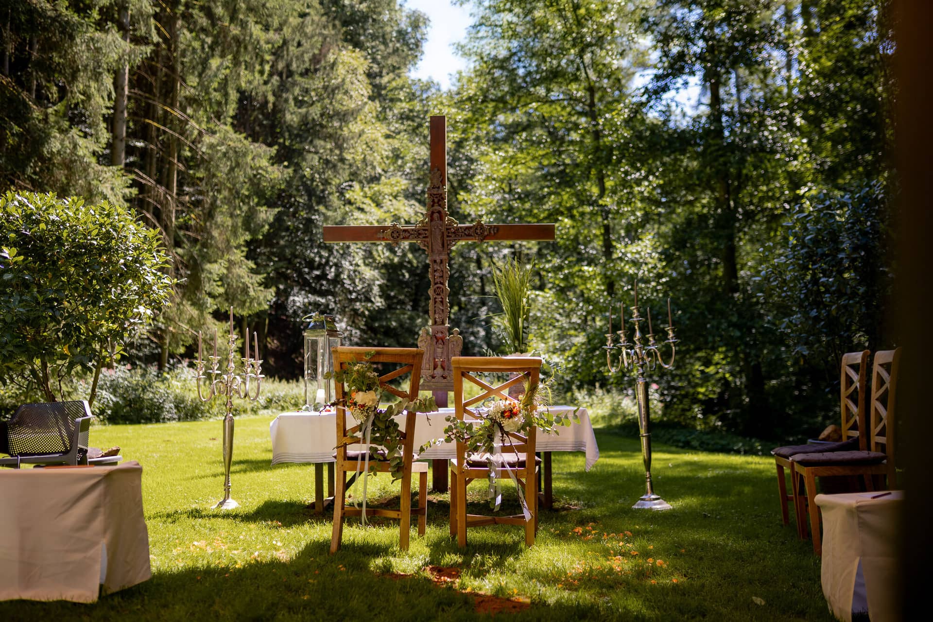 20230811 13 33 41 Hochzeit Elztal Hochzeitsfotograf Heiraten Heidelberg Landgasthof Heidersbacher Muehle 4K8A0437.B7KbsRX4 Romantische Trauungskulisse im Wald – Holzkreuz, floraler Schmuck, Stühle und Kerzenleuchter unter freiem Himmel