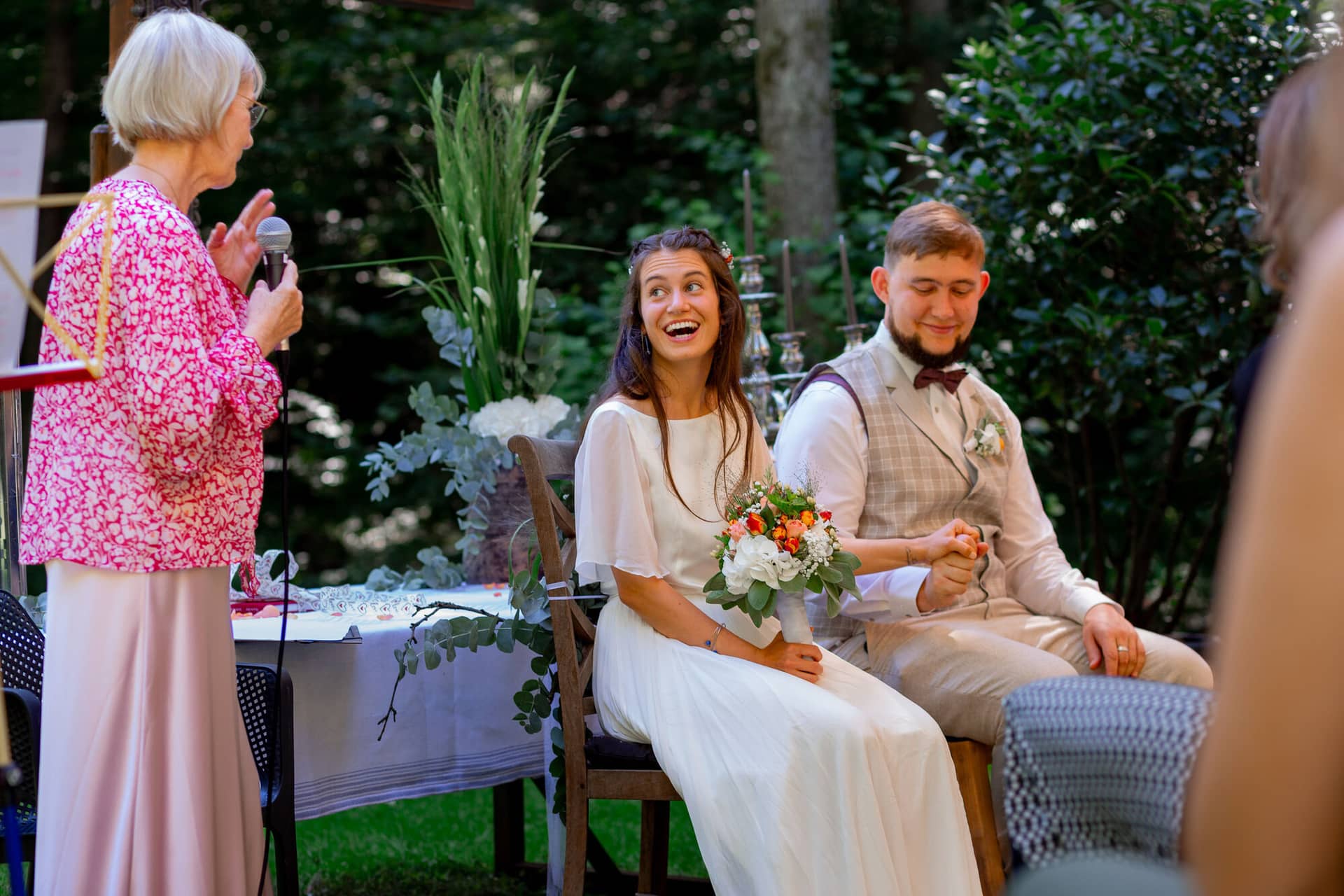 20230811 14 45 37 Hochzeit Elztal Hochzeitsfotograf Heiraten Heidelberg Landgasthof Heidersbacher Muehle MK3 8990.CuL1RXYy Traurednerin mit Mikrofon hält ihre persönliche Ansprache, Brautpaar hört aufmerksam zu