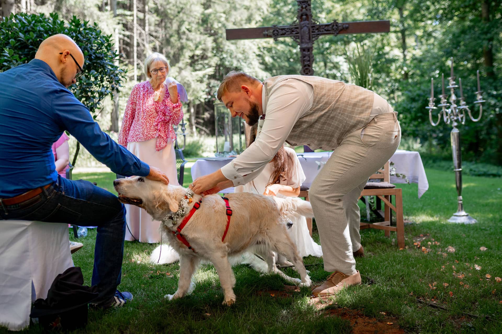 20230811 14 59 33 Hochzeit Elztal Hochzeitsfotograf Heiraten Heidelberg Landgasthof Heidersbacher Muehle 4K8A1788.P YlH4T4 Bräutigam mit Familienhund auf der Wiese, rustikaler Trauungsbereich mit Kreuz im Hintergrund
