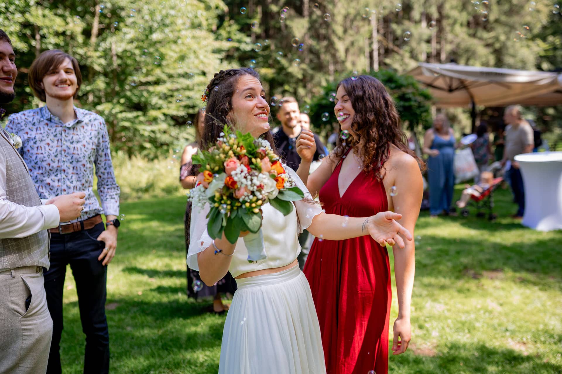 20230811 15 13 41 Hochzeit Elztal Hochzeitsfotograf Heiraten Heidelberg Landgasthof Heidersbacher Muehle 4K8A2583.B3oFFE59 Braut und Brautjungfer spielen ausgelassen Wasserbälle auf dem Rasen beim Sektempfang