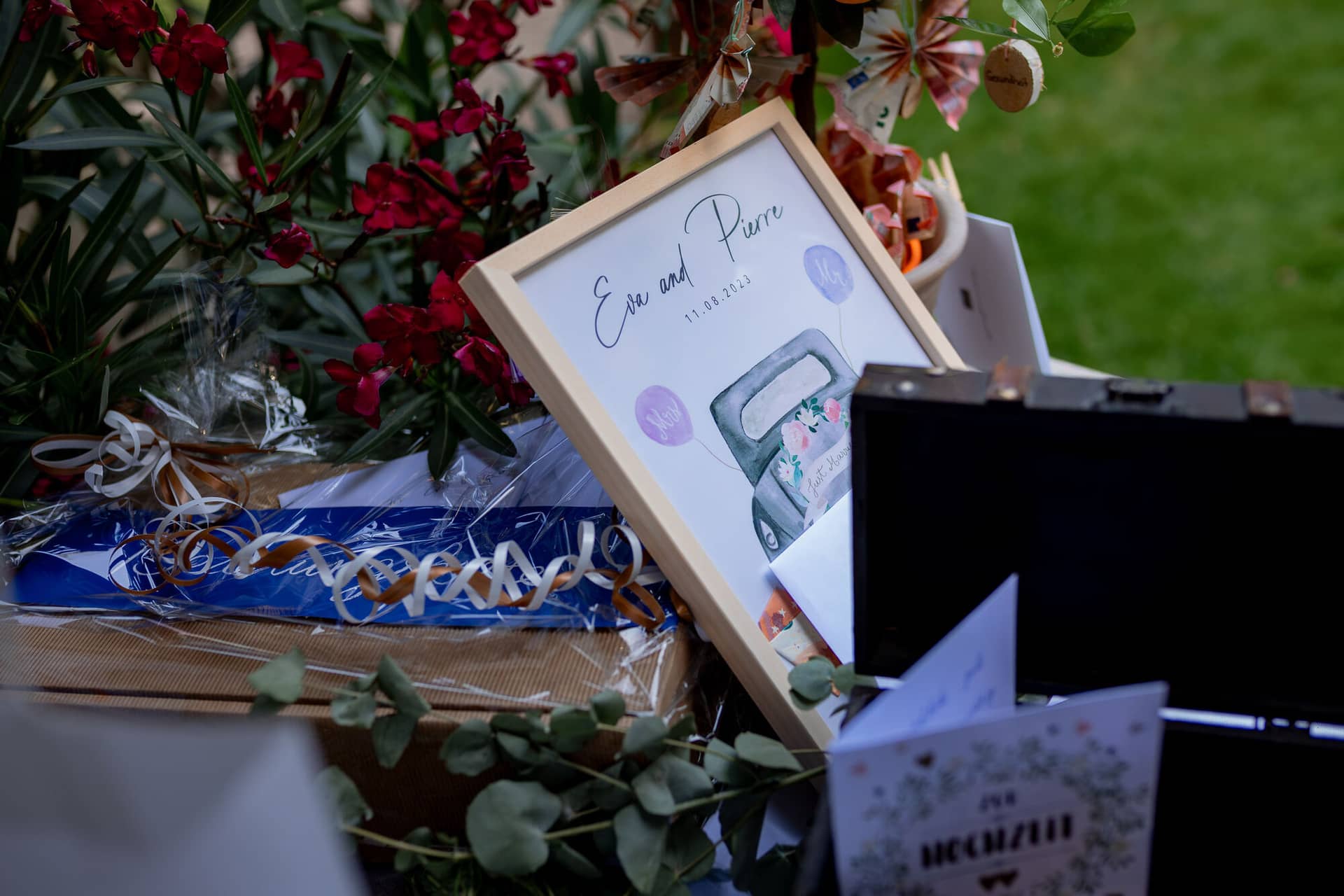 20230811 16 21 50 Hochzeit Elztal Hochzeitsfotograf Heiraten Heidelberg Landgasthof Heidersbacher Muehle 4K8A5243 Verbessert RR.CFYTliU Holzschild "Eva und Pierre" mit Hochzeitsdatum, Blumenstrauß und Koffer auf dem Empfangstisch