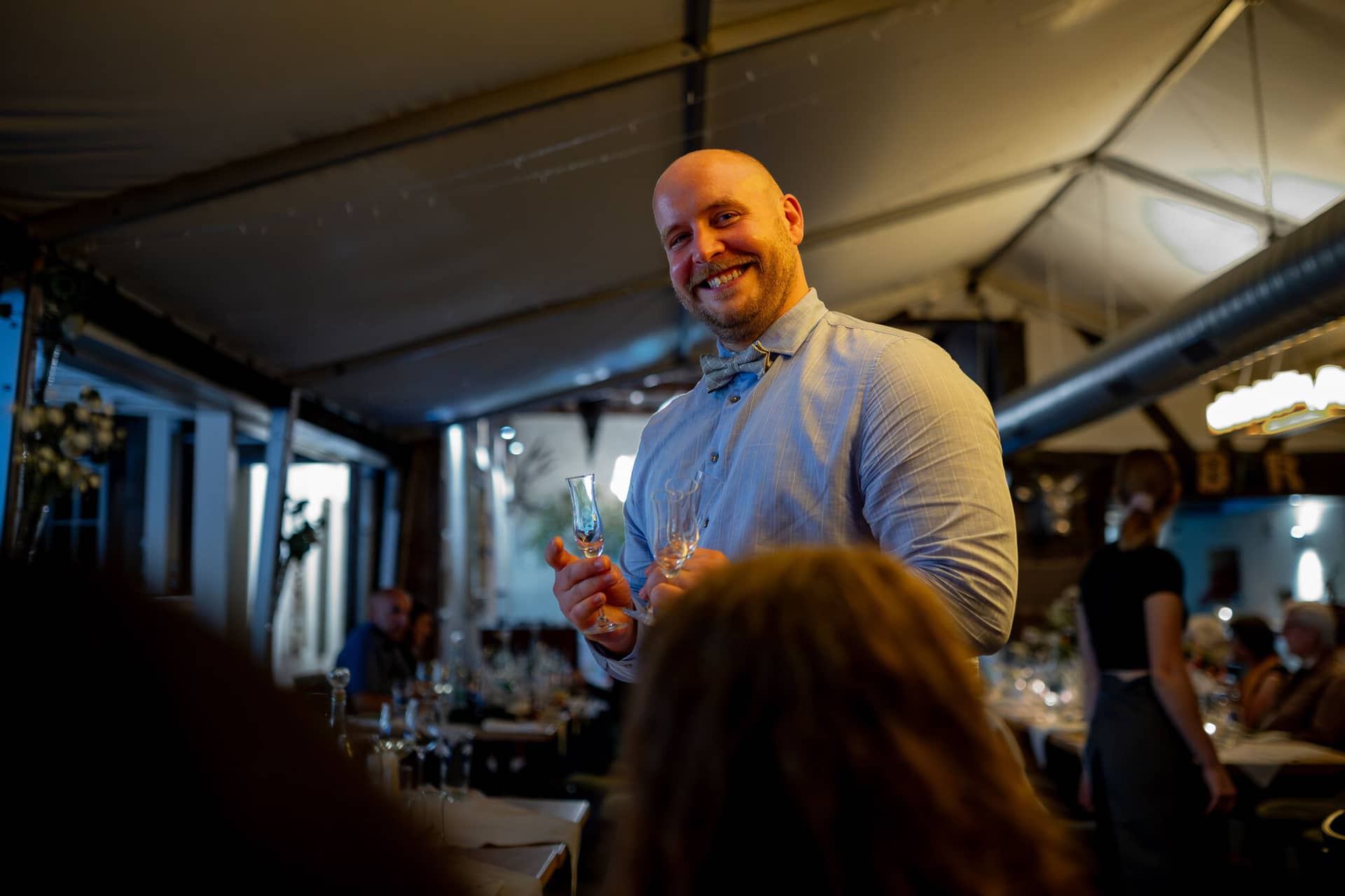 20230811 22 17 35 Hochzeit Elztal Hochzeitsfotograf Heiraten Heidelberg Landgasthof Heidersbacher Muehle 4K8A9348 Verbessert RR.DOpGc2FN Gast mit Glaskolben bei fröhlicher Degustationsrunde beim Hochzeitsabend