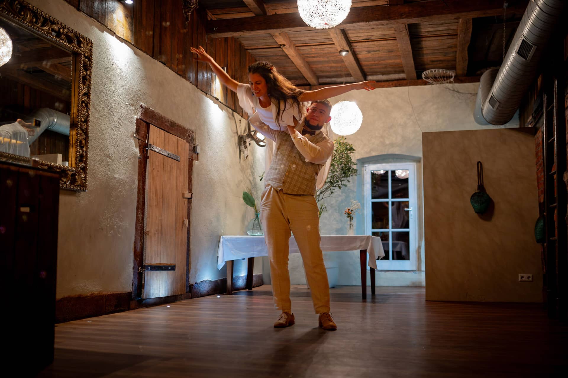 20230811 22 32 30 Hochzeit Elztal Hochzeitsfotograf Heiraten Heidelberg Landgasthof Heidersbacher Muehle 4K8A9767 Verbessert RR.BkivlkId Bräutigam trägt die Braut tanzend durch den rustikalen Holzraum der Feierlocation