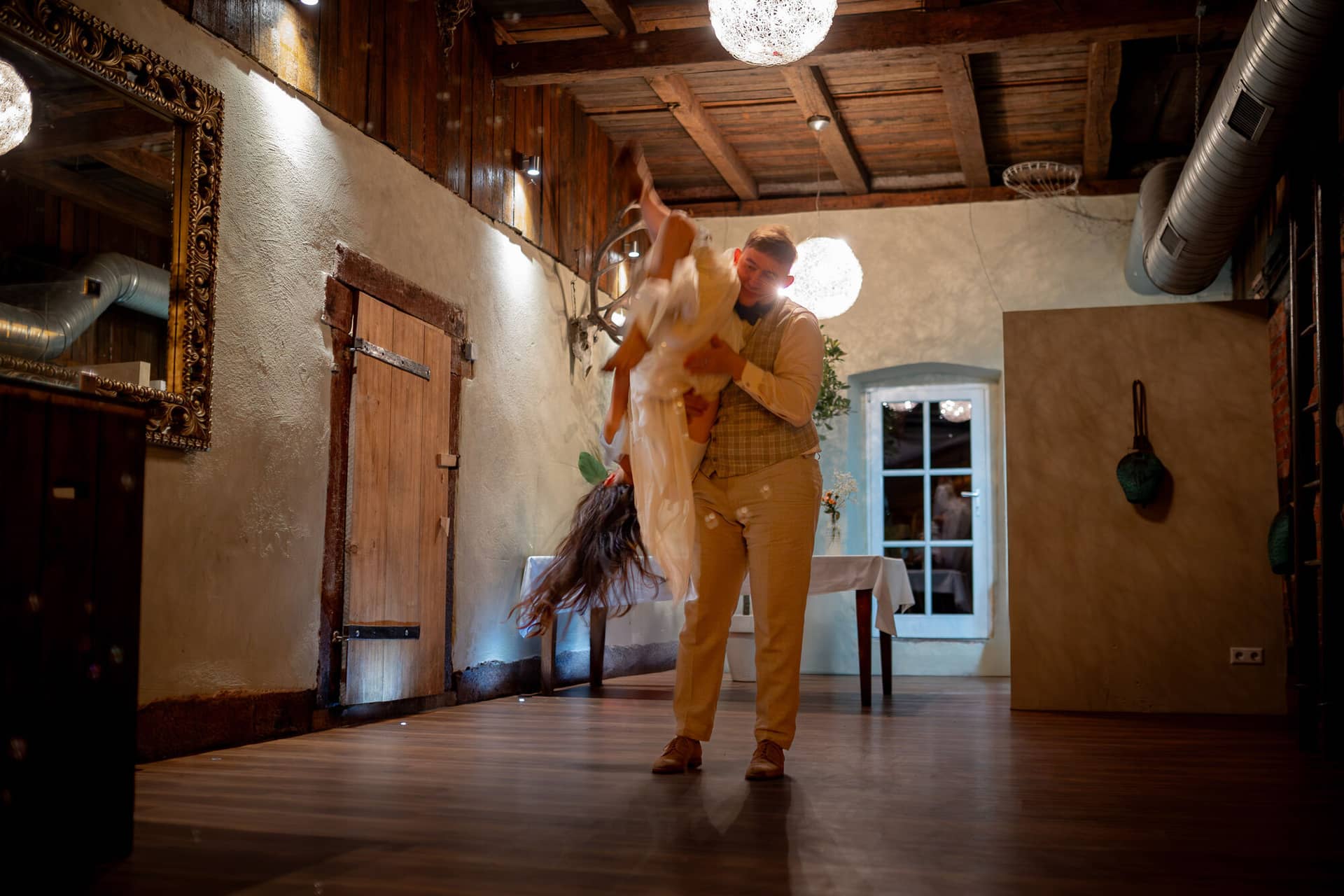 20230811 22 32 31 Hochzeit Elztal Hochzeitsfotograf Heiraten Heidelberg Landgasthof Heidersbacher Muehle 4K8A9776 Verbessert RR.BsEt6xXS Bräutigam dreht die Braut im Walzer unter den Hängeleuchten des Holzsaals der Mühle