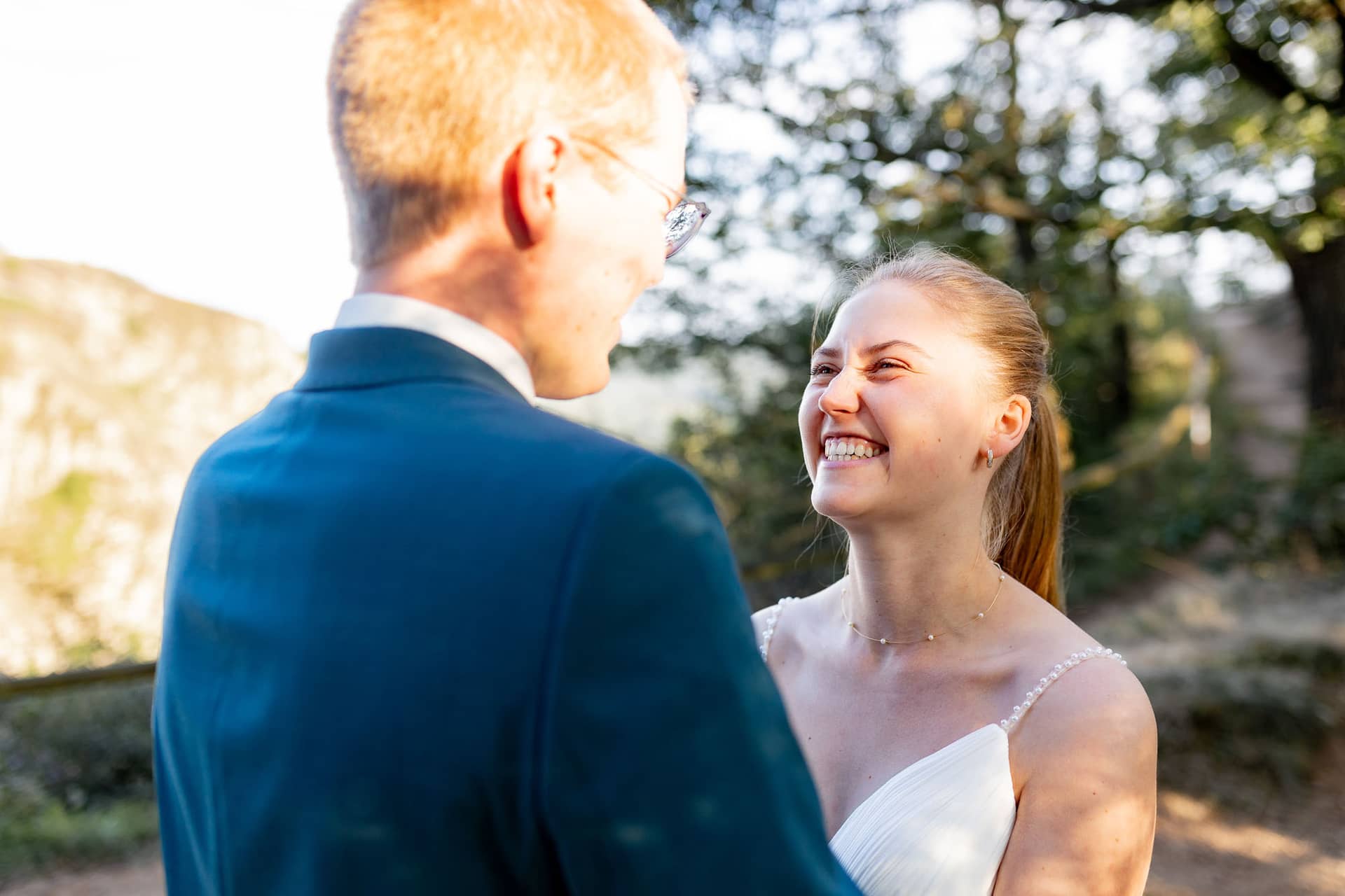 20240728 19 27 53 Ropertz Bad MüNster Ebernburg 4K8A2051.B31f8icA Braut und Bräutigam lächeln sich unter Bäumen an beim Brautpaarshooting an der Burg Ebernburg