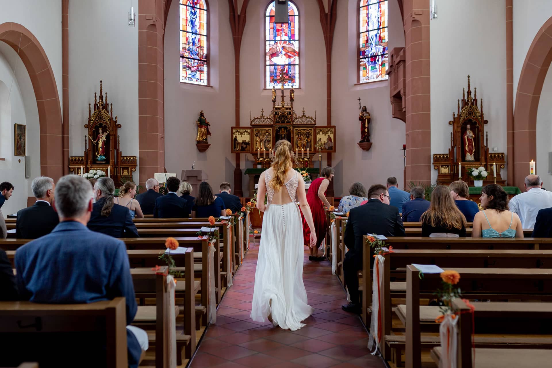 20240803 125306 4K8A3142.D9o Ji4B Braut geht den Kirchenmittelgang zur Trauung in St. Johannes der Täufer Bad Münster entlang