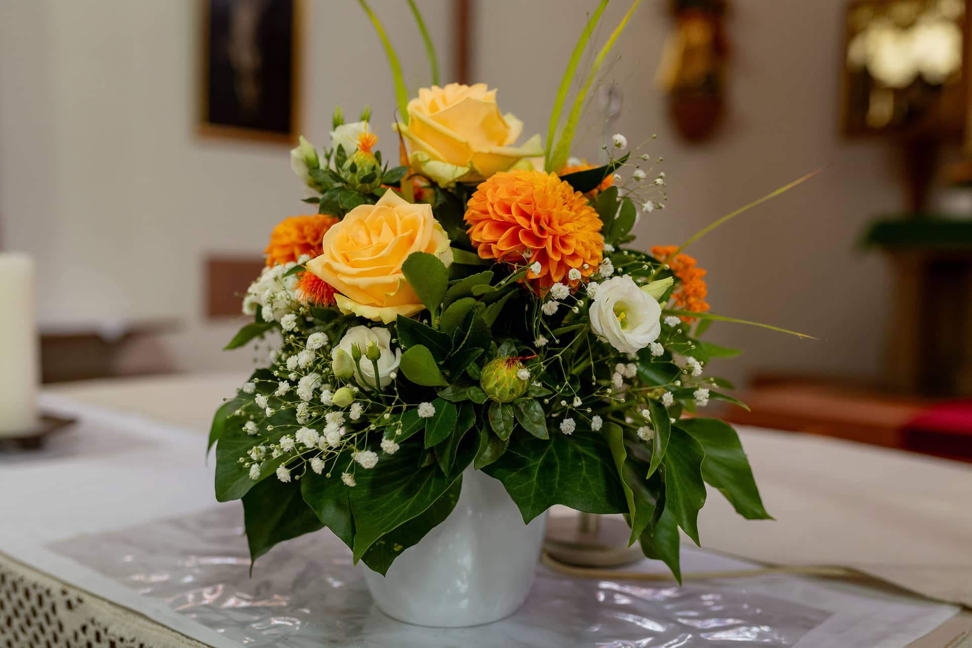 20240803 141210 4K8A7239.BpD1LR68 Blumenarrangement mit roten und gelben Rosen auf dem Tisch vor dem Kirchenaltar