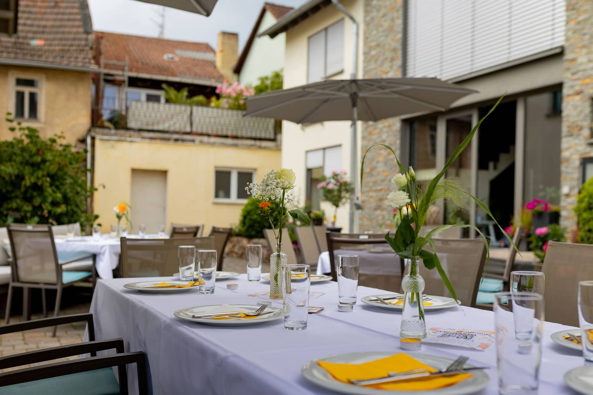 20240803 144230 4K8A7391.24ZnlKPE Festlich gedeckter Tisch mit Blumendekoration und Sonnenschirm im Garten des Wallhäuser Weintreffs