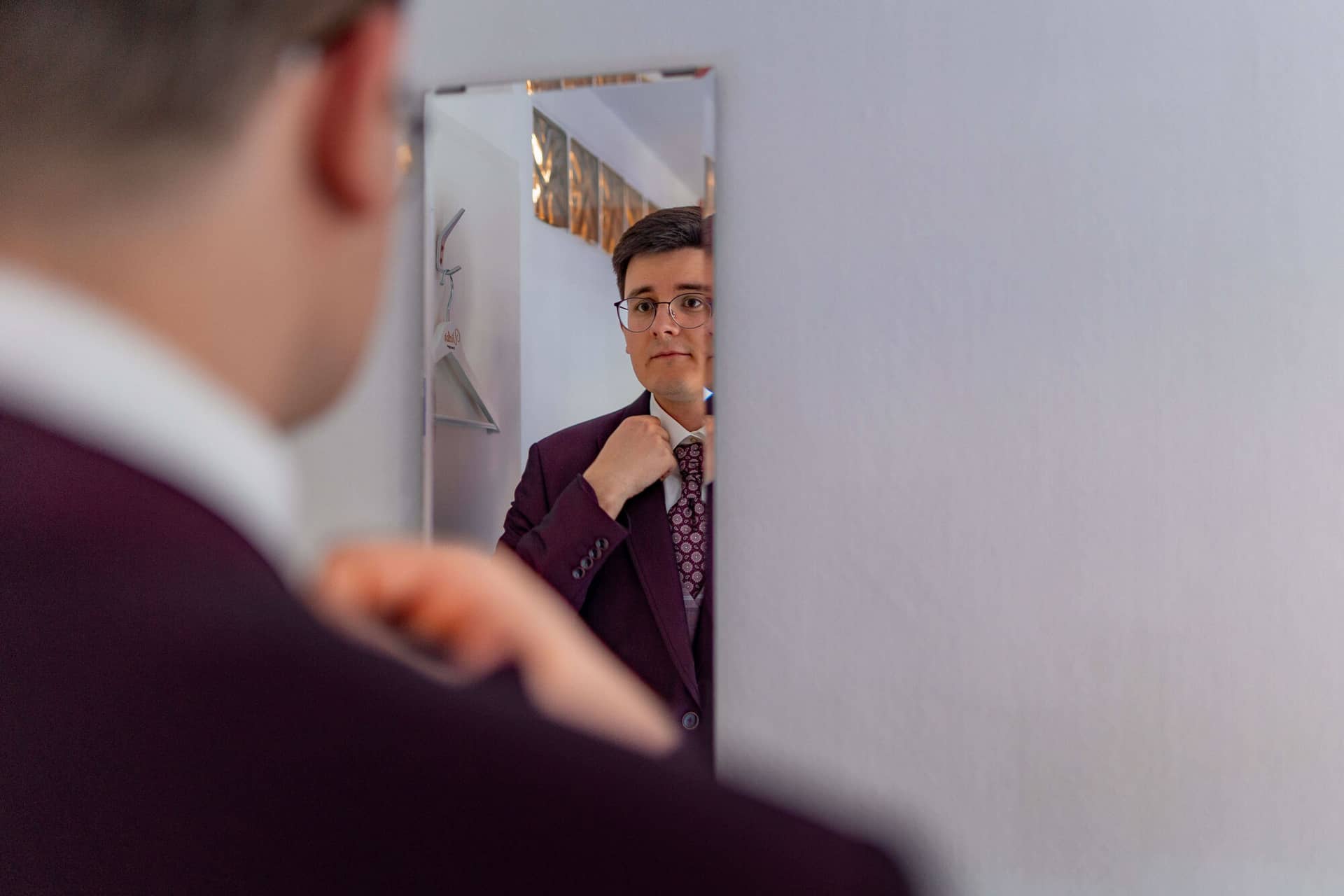 20250501 11 37 594K8A2534 Getting Ready Brautigam Bad Duerkheim.BONi5WIb Bräutigam richtet Krawatte vor dem Spiegel im bordeaux Hochzeitsanzug