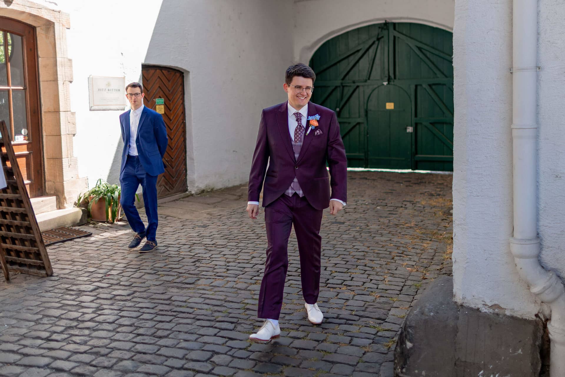 20250501 13 51 584K8A2917 First Loog Innenhof Fritz Ritter Bad Duerkheim.BhN4ppZb Bräutigam im bordeaux Hochzeitsanzug betritt den Innenhof zum First Look