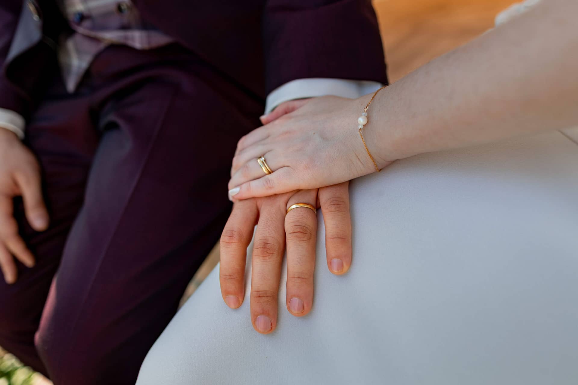 20250501 17 29 354K8A5644 Brautpaarshooting Bad Duerkheim Fritz Ritter Hochzeitsfotograf.CRMj2bGR Detailaufnahme goldener Eheringe und Perlenarmband auf den Händen der Braut