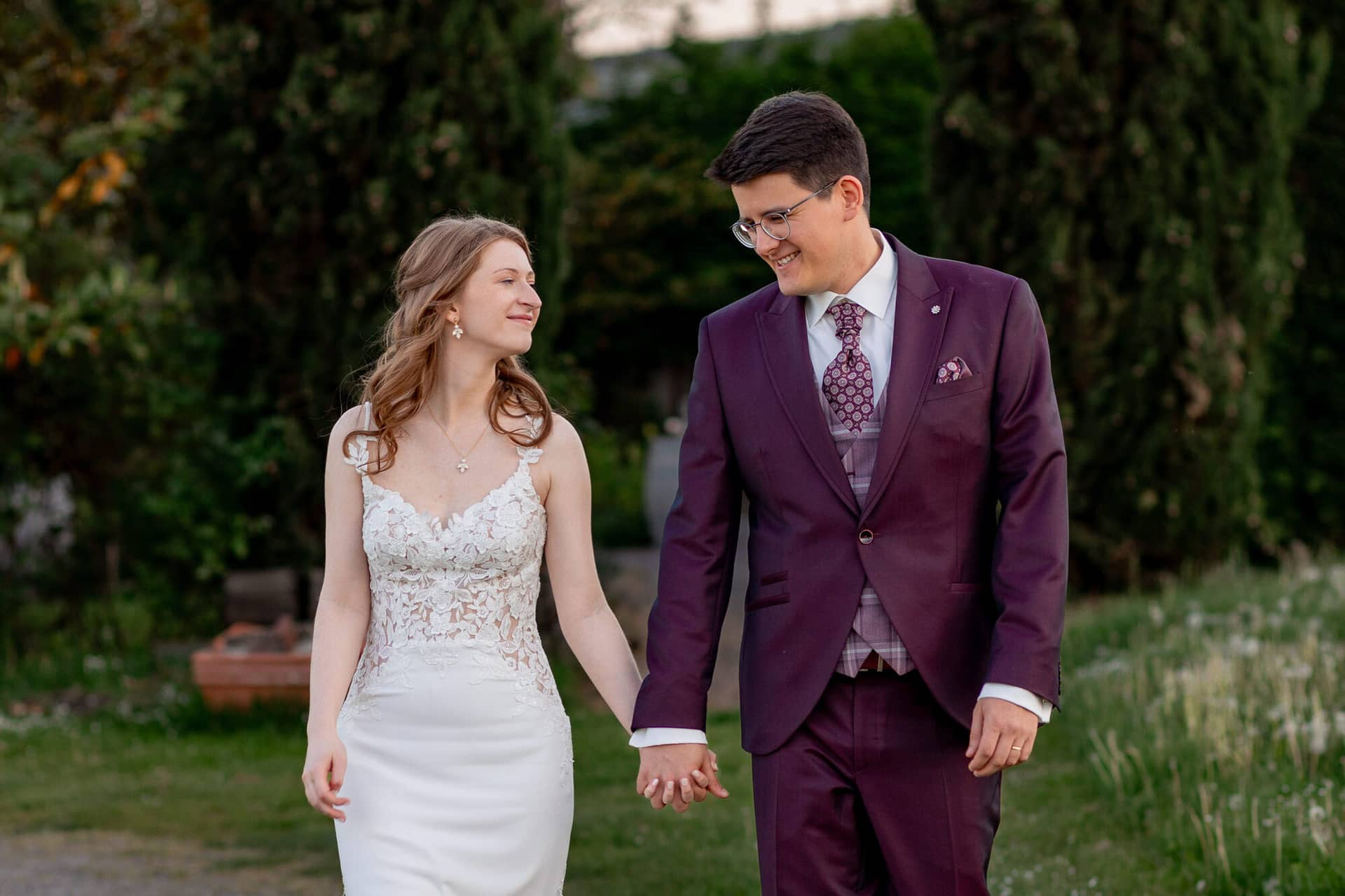 20250501 20 07 532C4A3805 Brautpaarshooting Sunnenuntergang Golden Hour Bad Duerkheim Fritz Ritter Hochzeitsfotograf.DAthyCY2 Brautpaar spaziert Hand in Hand mit Blick auf die Weinberge im Abendlicht