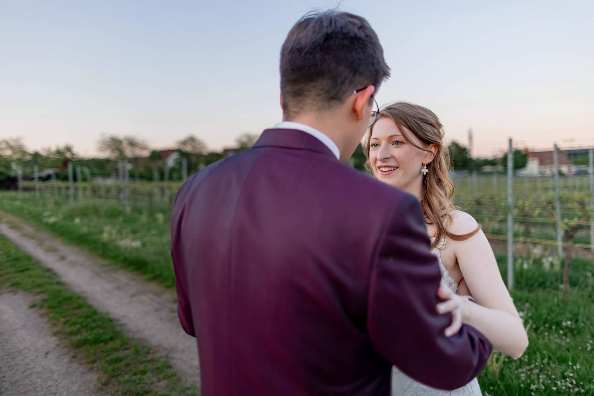 20250501 20 10 204K8A6650 Brautpaarshooting Sunnenuntergang Golden Hour Bad Duerkheim Fritz Ritter Hochzeitsfotograf.BIZFlBjz Strahlende Braut lacht glücklich beim Tanzen mit dem Bräutigam im Weinberg