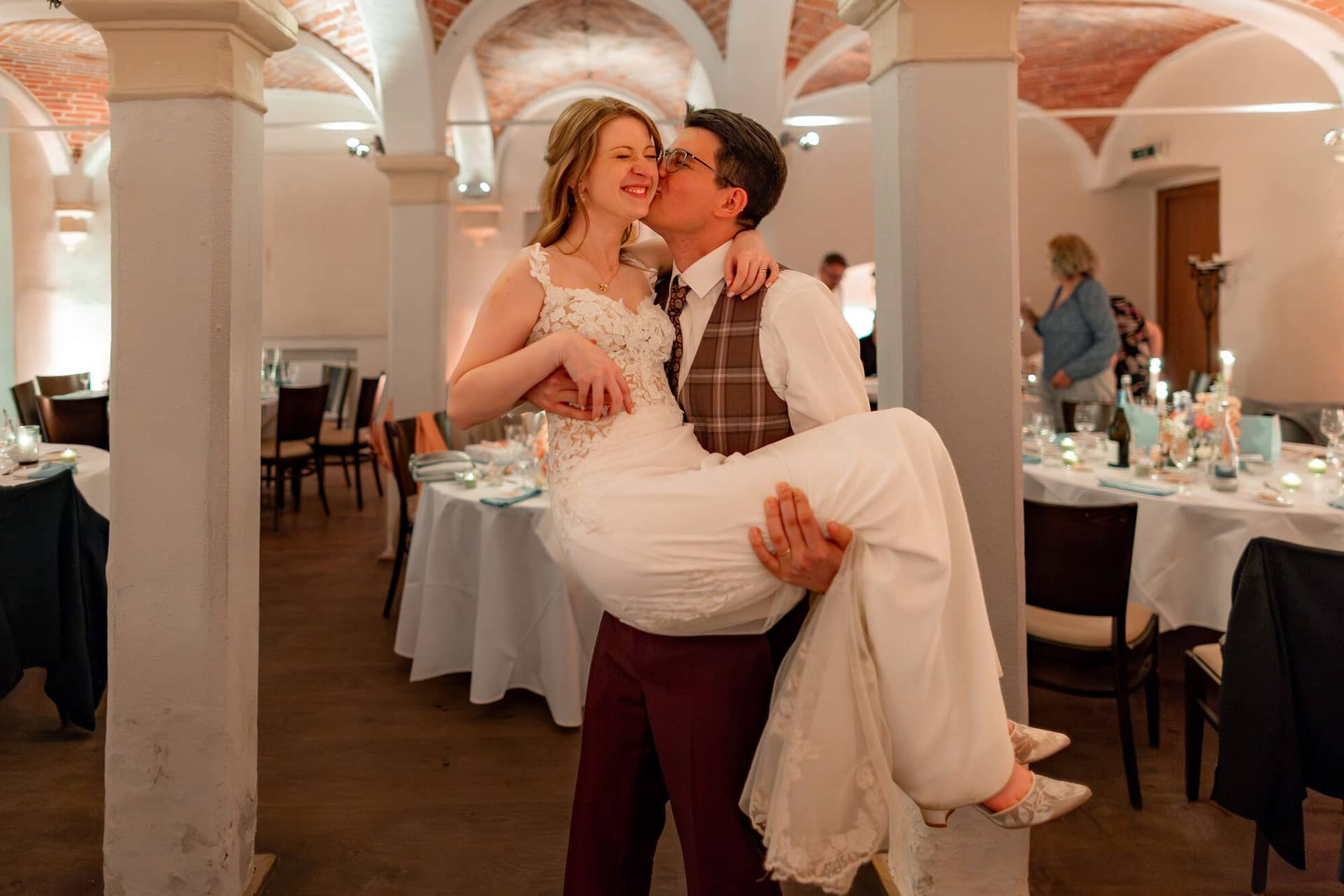 20250501 22 49 214K8A7730 Verbessert RR Hochzeitsfeier Party Bad Duerkheim Fritz Ritter Hochzeitsfotograf.DENPmKiw Bräutigam trägt seine Braut auf den Armen im Kreuzgewölbesaal