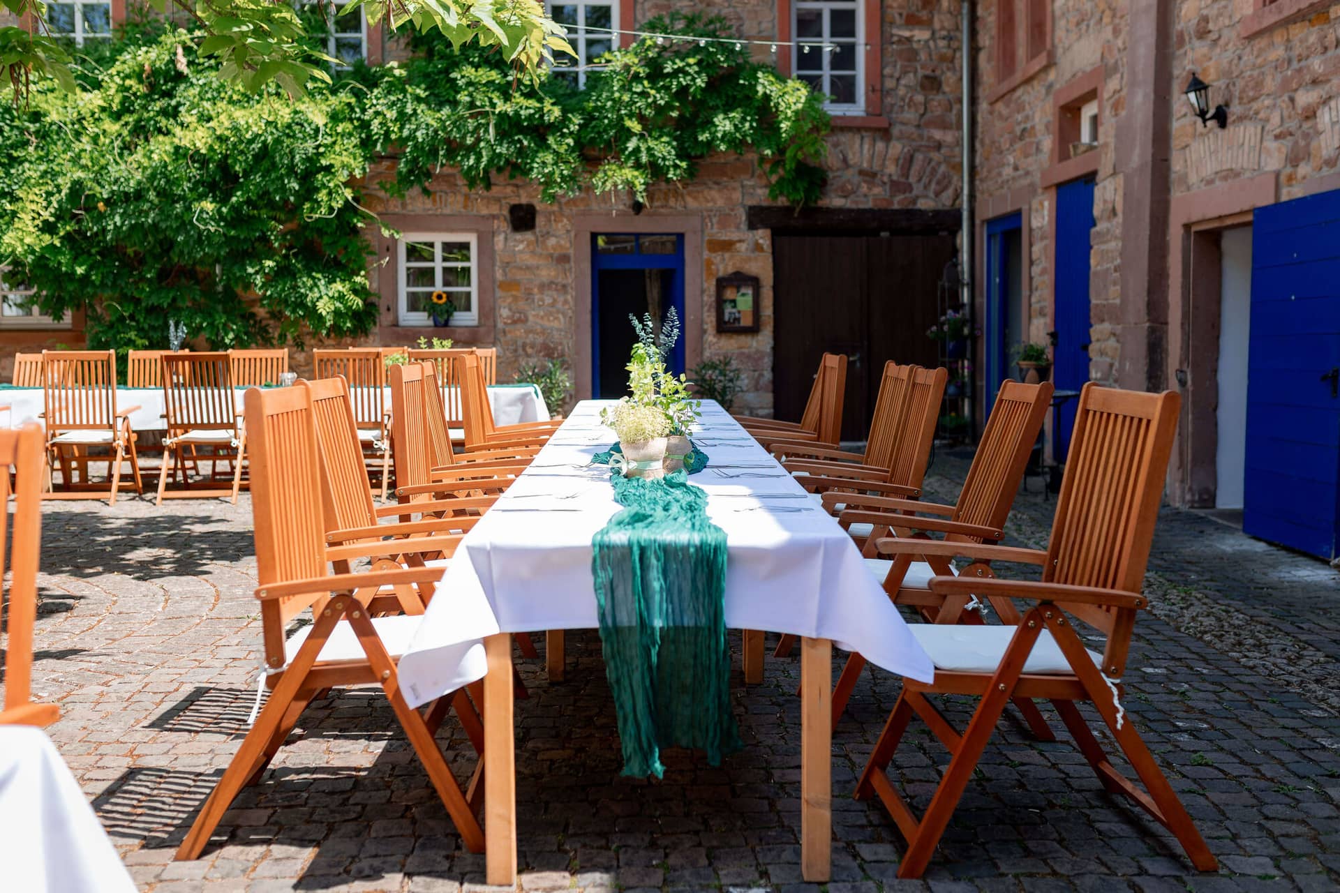 20250621 14 20 32 4K8A1359.C5hHwaWm Innenhof mit langen Hochzeitstafeln und grünem Läufer