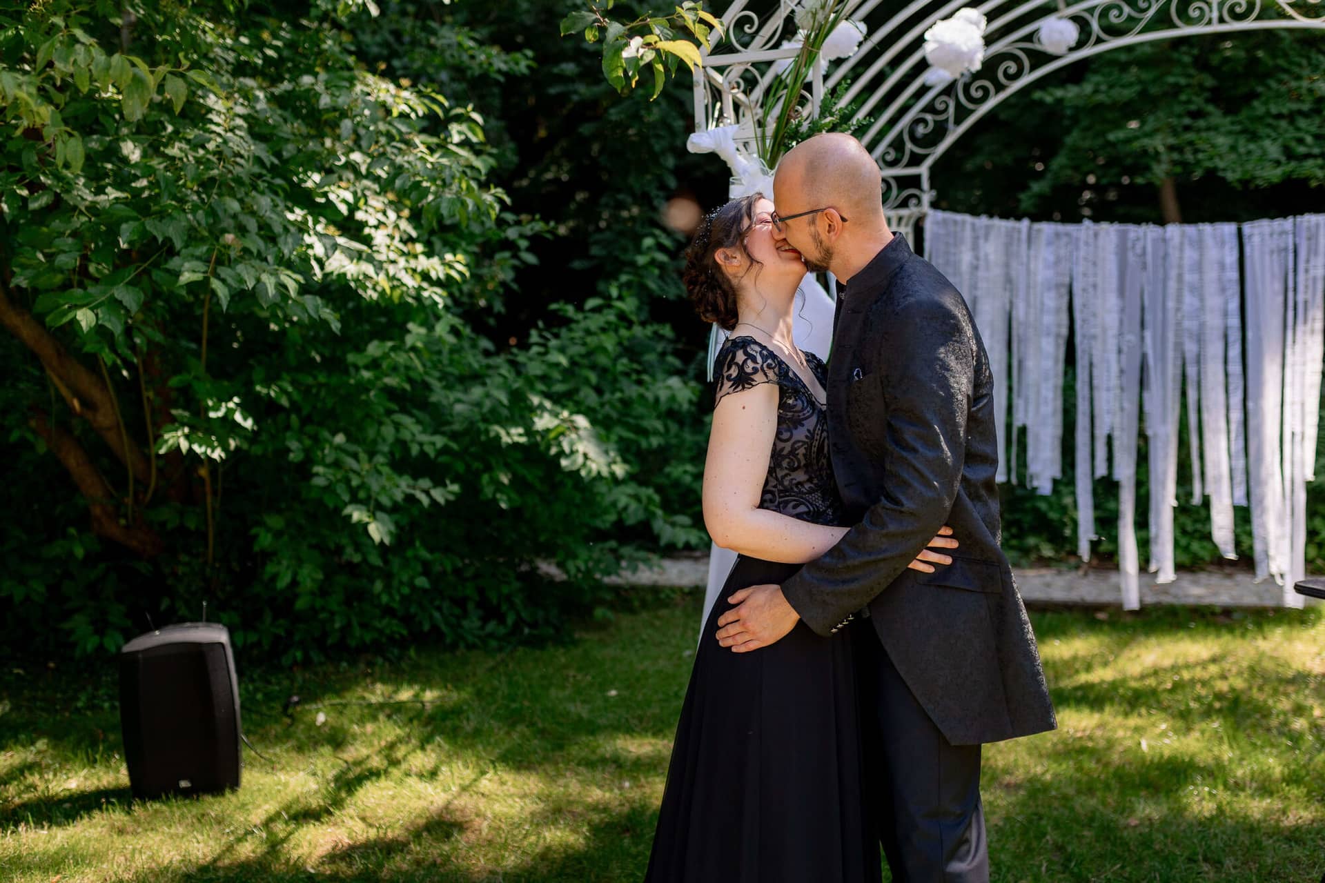 20250621 16 13 18 4K8A2290 Trauung Felsenmuehle Neuleinigen.CkBGgAw Brautpaar unter dem weißen Traubogen umgeben von Gästen