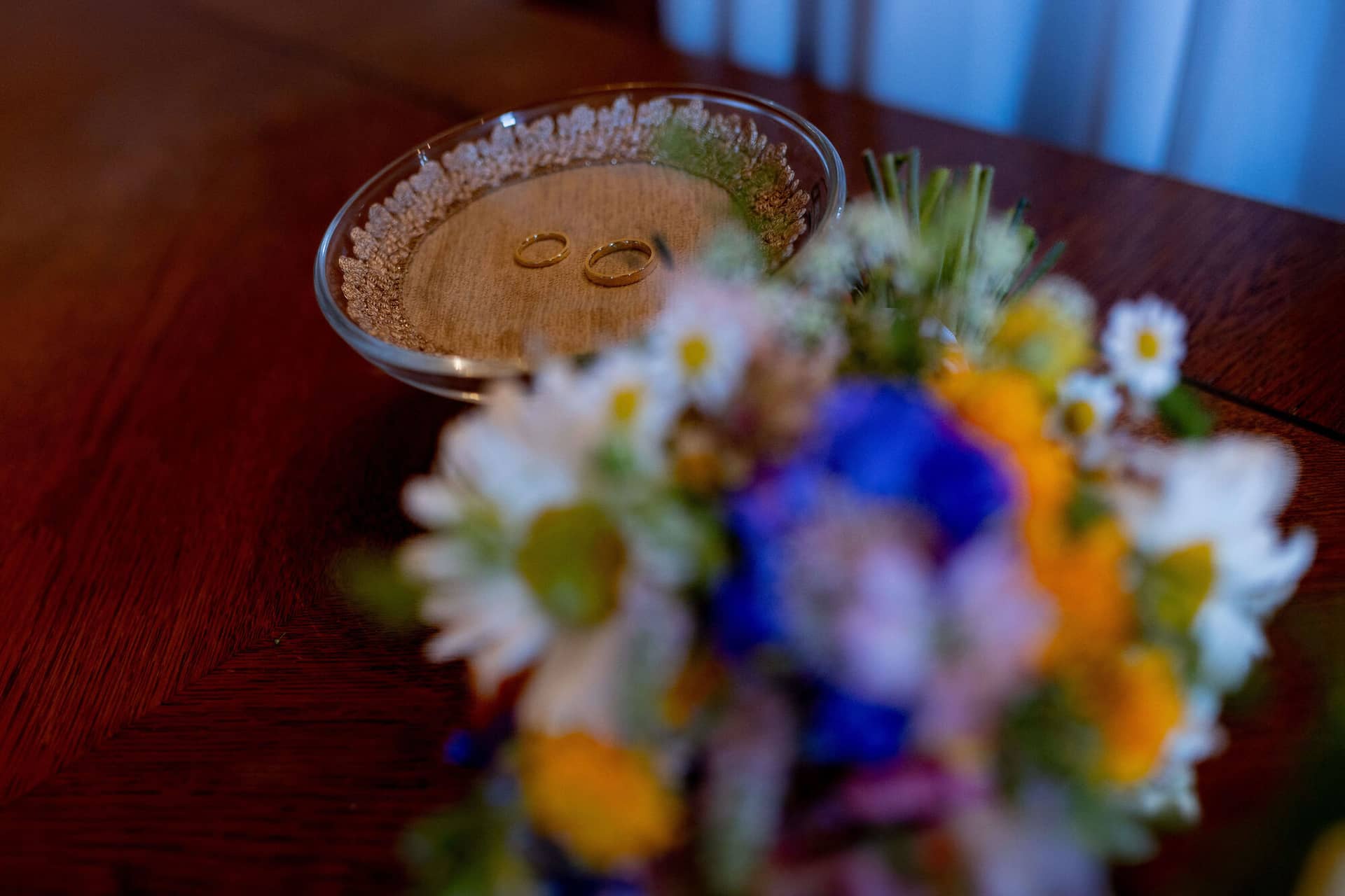 20250830 13 29 44 4K8A0250.BvNGL47 Eheringe auf einem Ringkissen neben buntem Brautstrauß