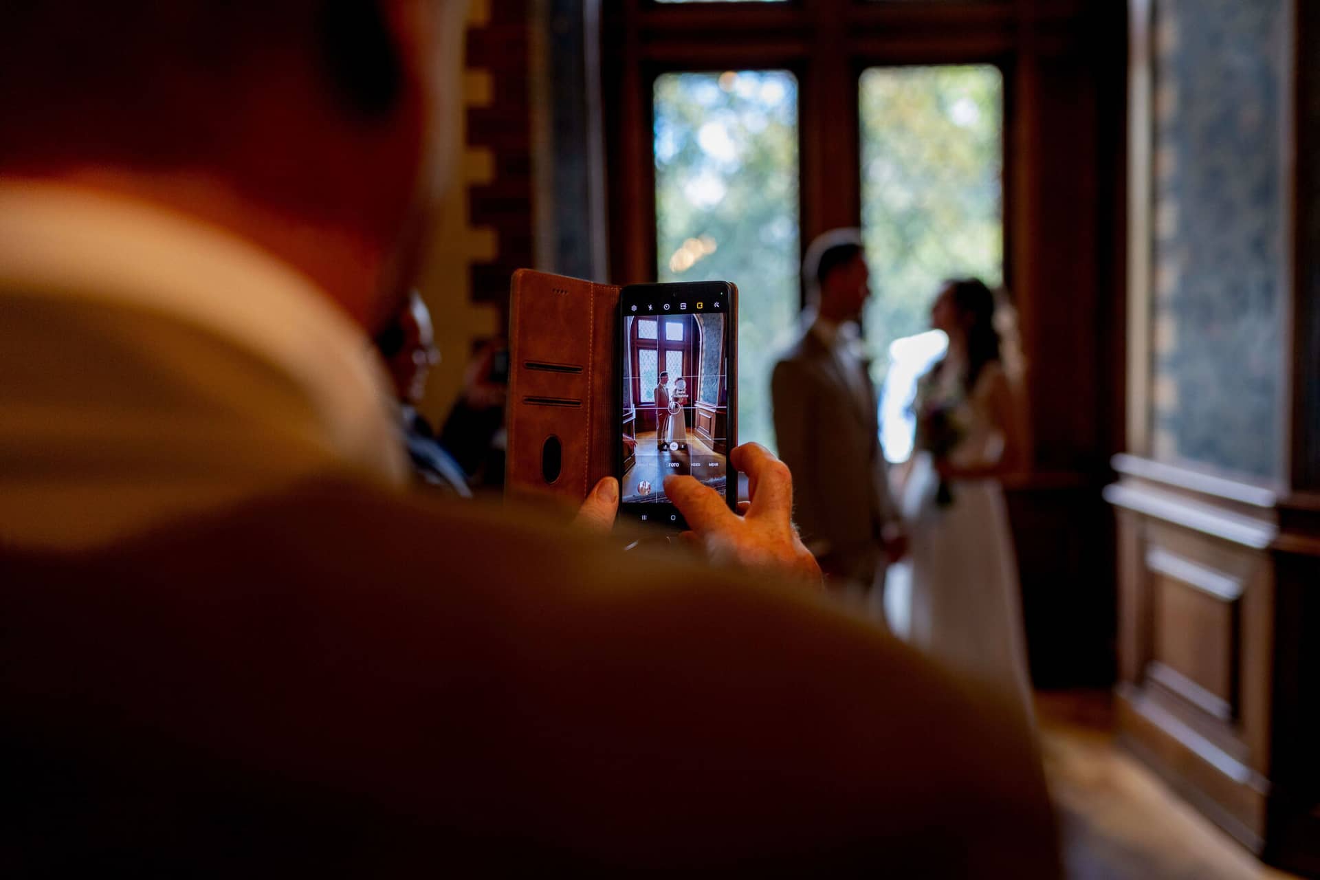 20250830 13 41 01 4K8A0576.CIE9jxYp Hochzeitsgast filmt das Brautpaar mit dem Smartphone im Standesamt