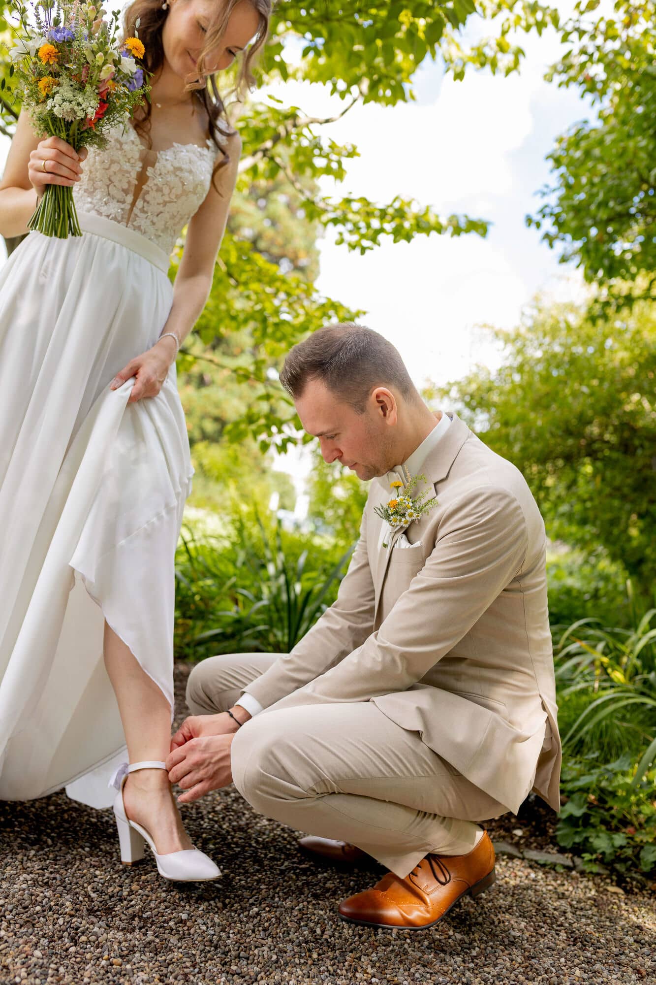 20250830 14 21 50 4K8A1281.DsSaxKU9 Bräutigam richtet der Braut den Schuh im Garten des Hermannshofs