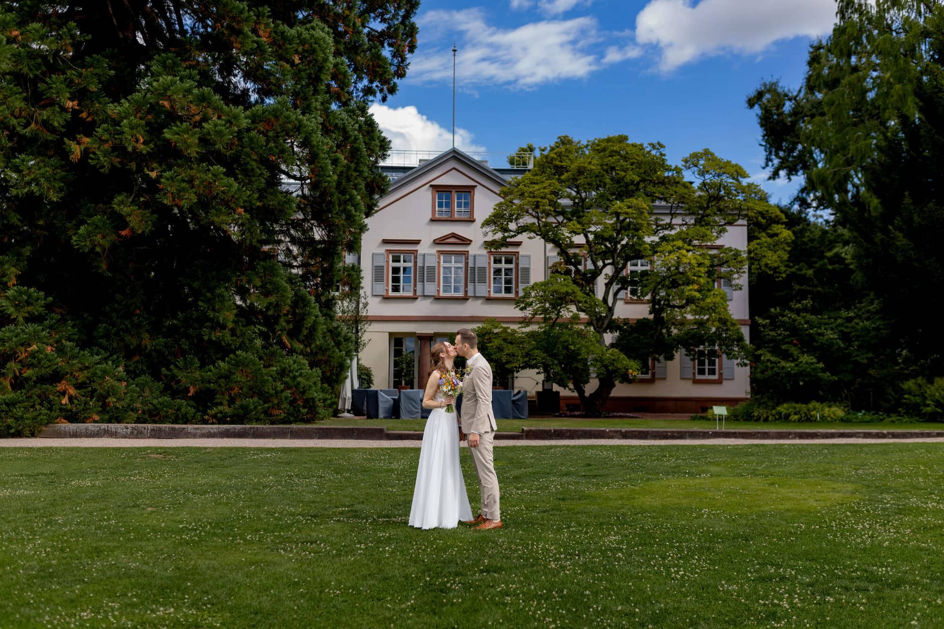 20250830 14 33 03 4K8A1468.D3kVO36q Brautpaar küsst sich auf der Wiese vor dem Herrenhaus im Hermannshof