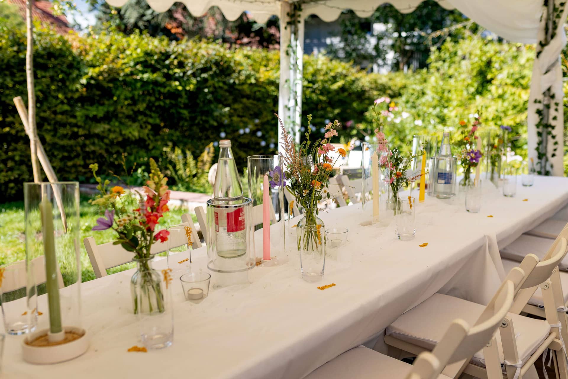 20250830 15 05 48 4K8A1563.CN4WqFeN Dekorierter Hochzeitstisch mit Wildblumensträußen und rosa Kerzen unter dem Gartenzelt