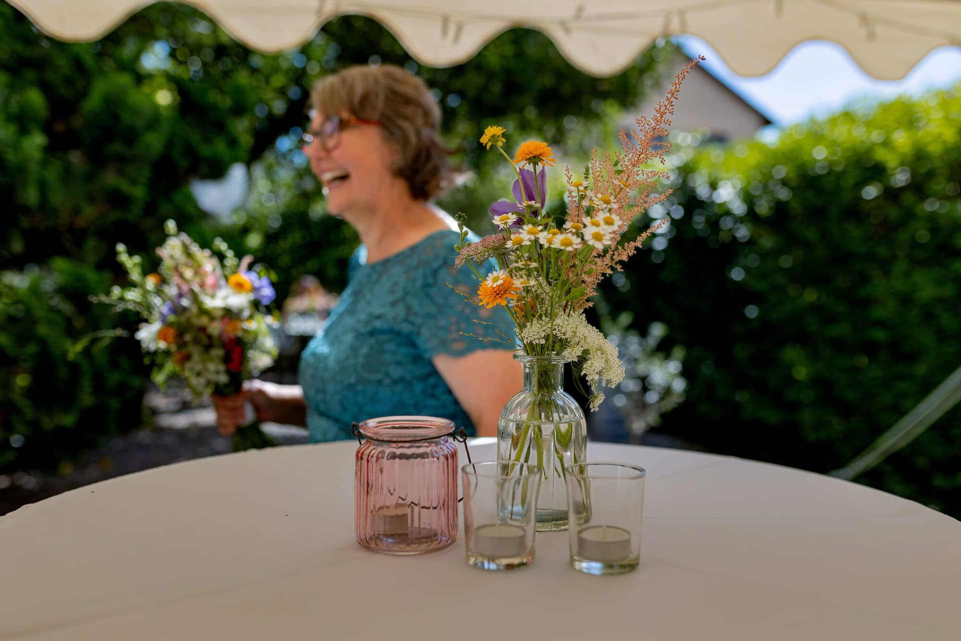 20250830 15 08 30 4K8A1610.CLccj Yh Stehtisch mit Blumenvase und Windlicht im Garten mit lachender Gästin