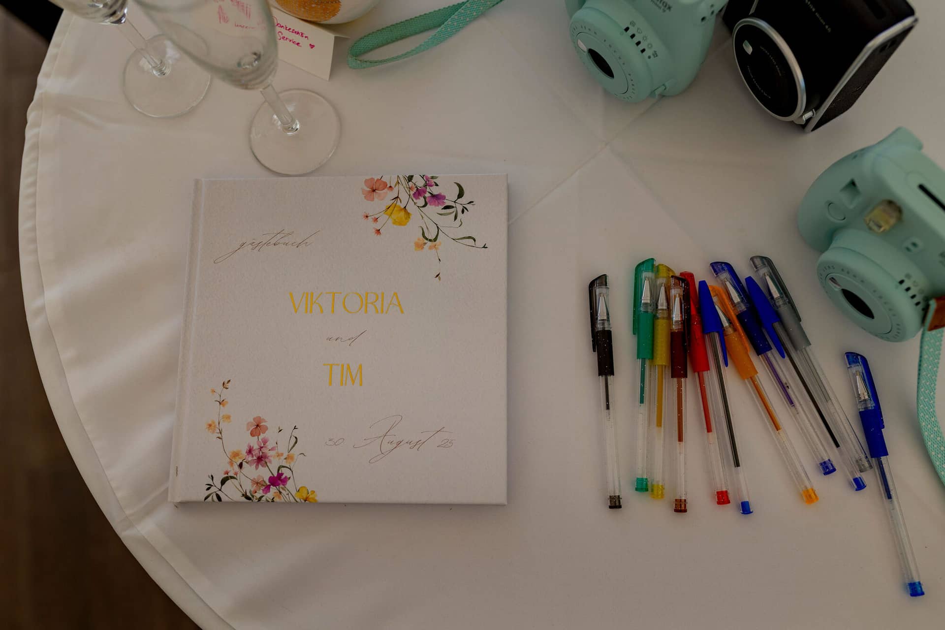 20250830 15 08 51 4K8A1615.DER0Ti27 Gästebuch mit Aufschrift Viktoria und Tim neben Instax-Kameras und bunten Stiften