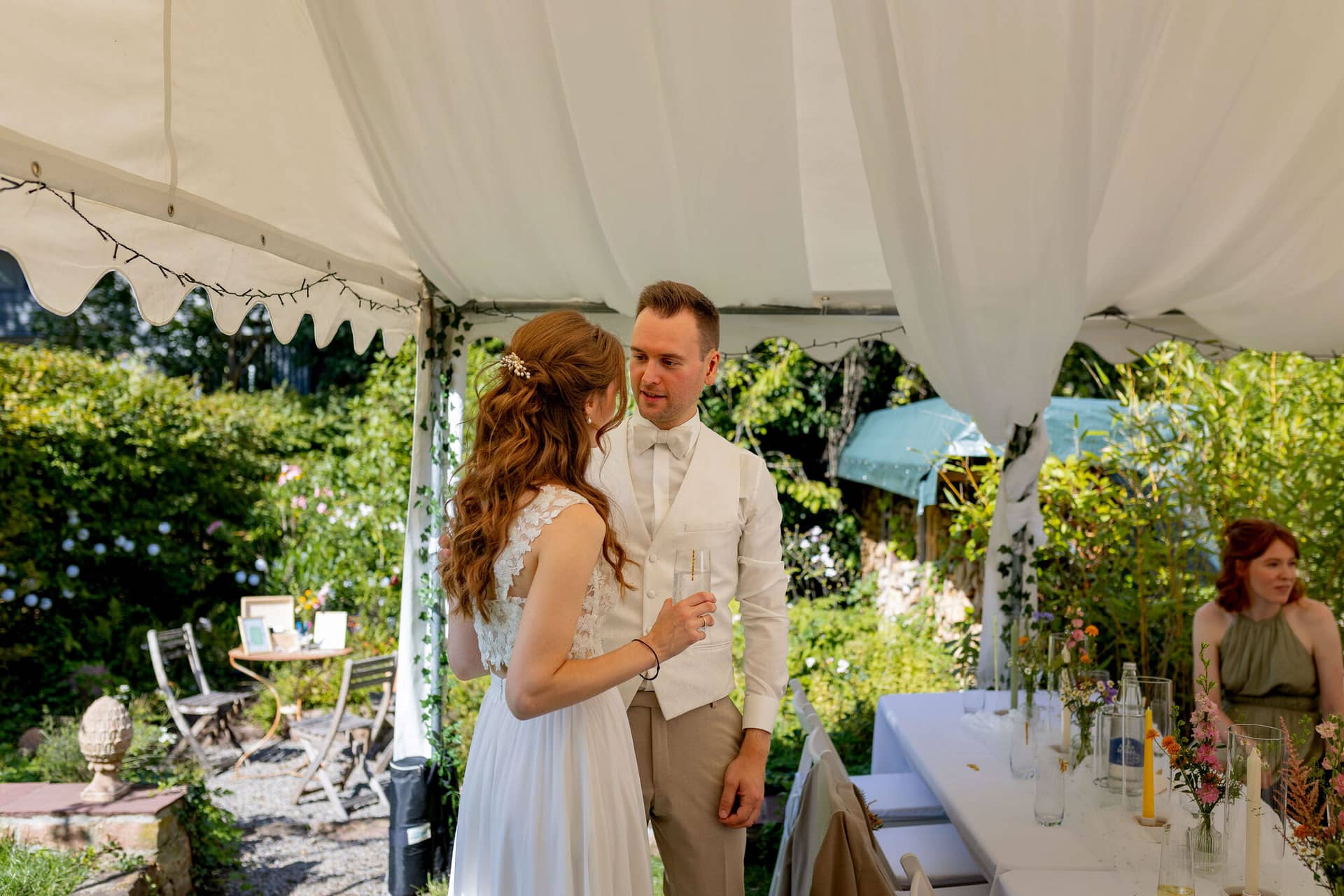 20250830 15 29 39 4K8A1685.II7gmdZA Brautpaar unterhält sich mit Sektgläsern unter dem Gartenzelt